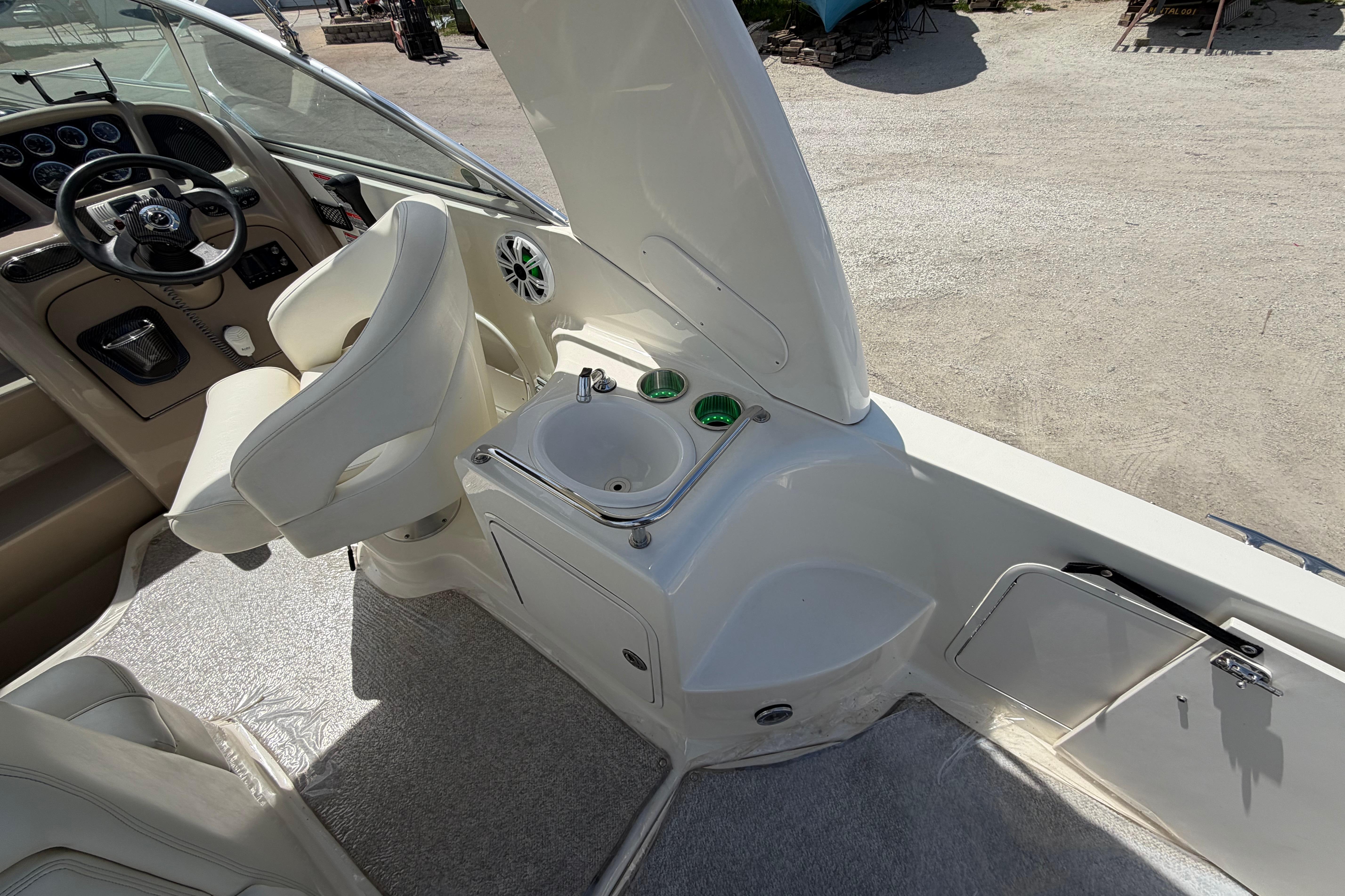 2004 Sea Ray Sundancer 260 cockpit with steering wheel, sink, and seating area.
