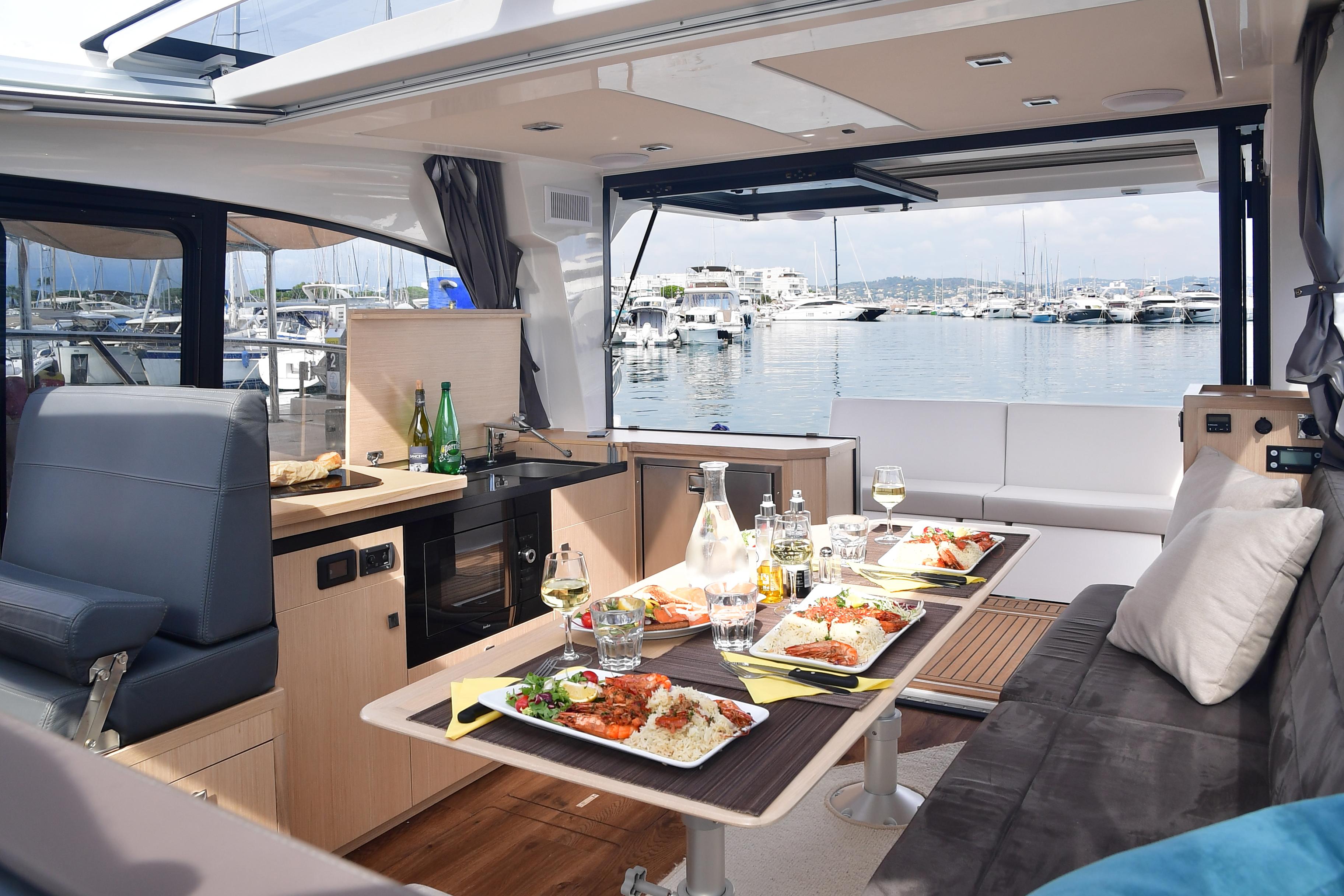 Luxurious interior of 2025 Skamander Monaco Coupe yacht with dining setup and marina view.