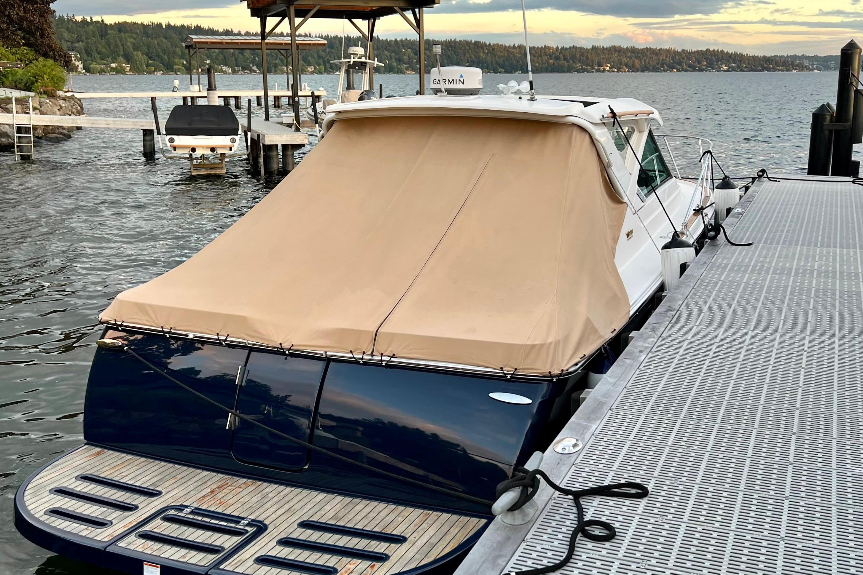 2014 Tiara Yachts 3100 Coronet docked, featuring a beige cover and scenic waterfront.