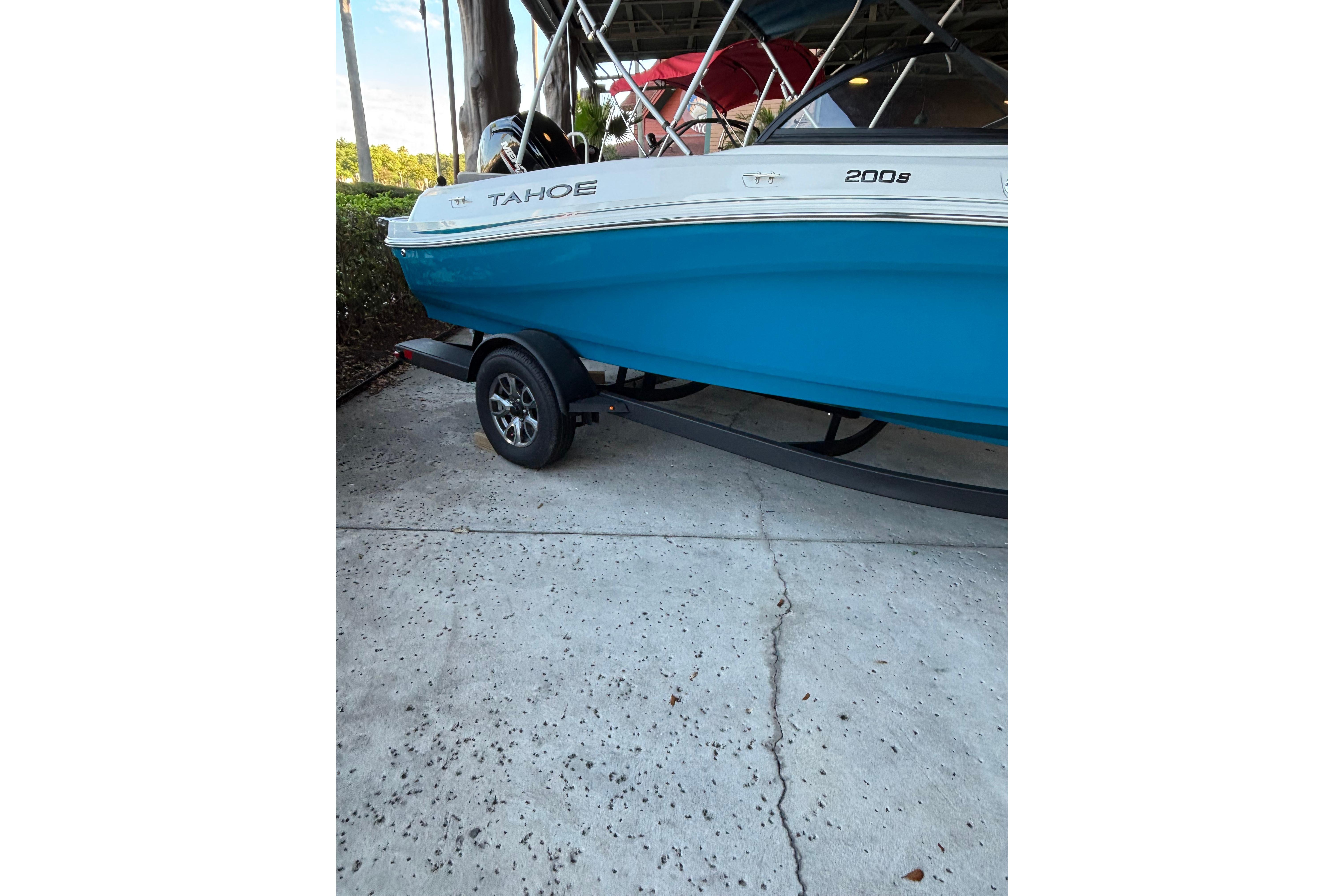 2025 Tahoe 200 S boat on trailer, blue and white design, parked on concrete.