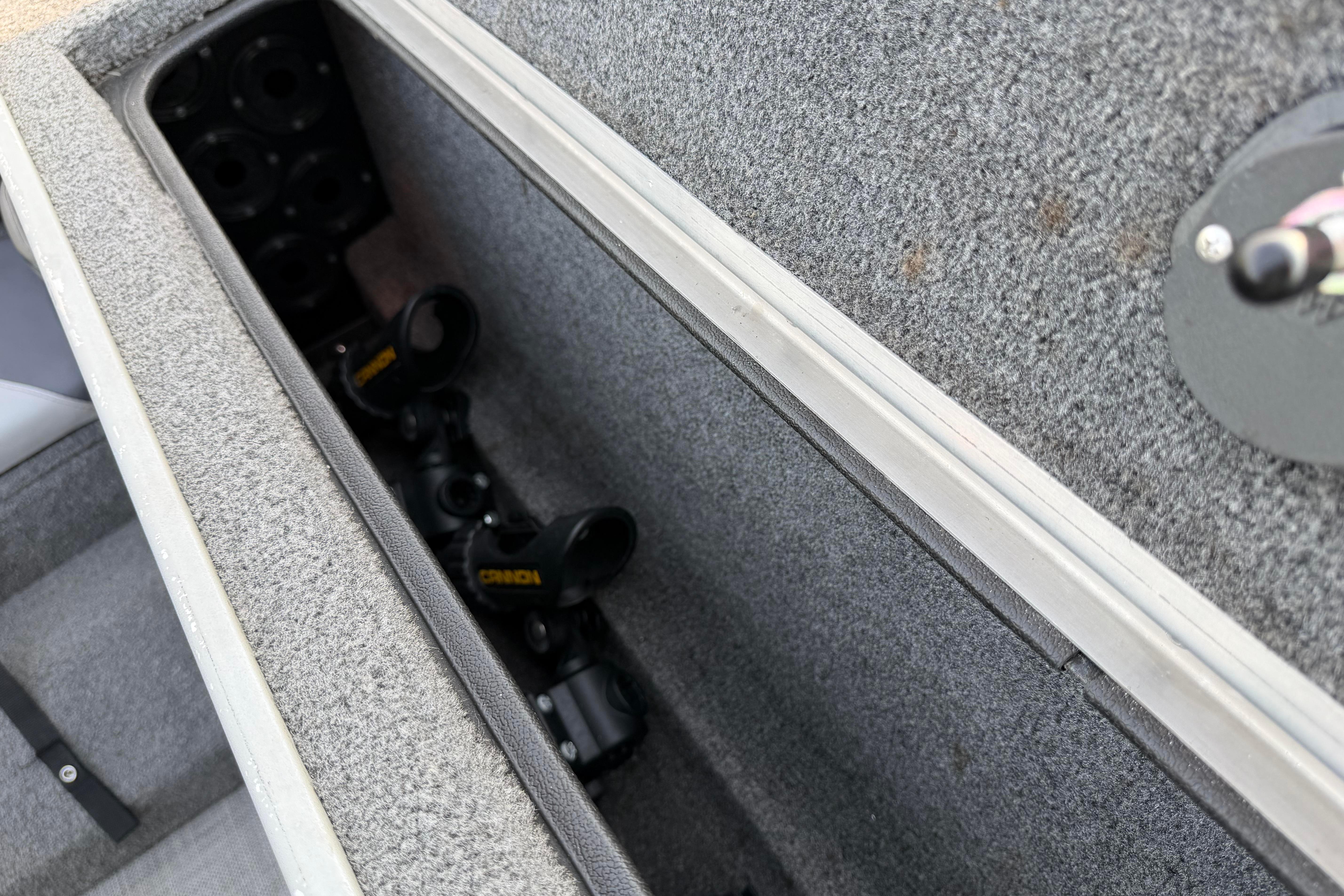 Storage compartment in 2019 Alumacraft Trophy 205 boat, featuring rod holders.