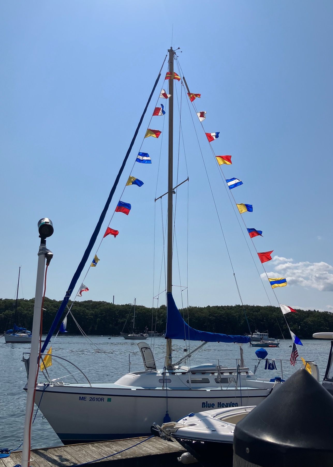 1975 O'Day Sloop adorned with colorful flags in harbor.