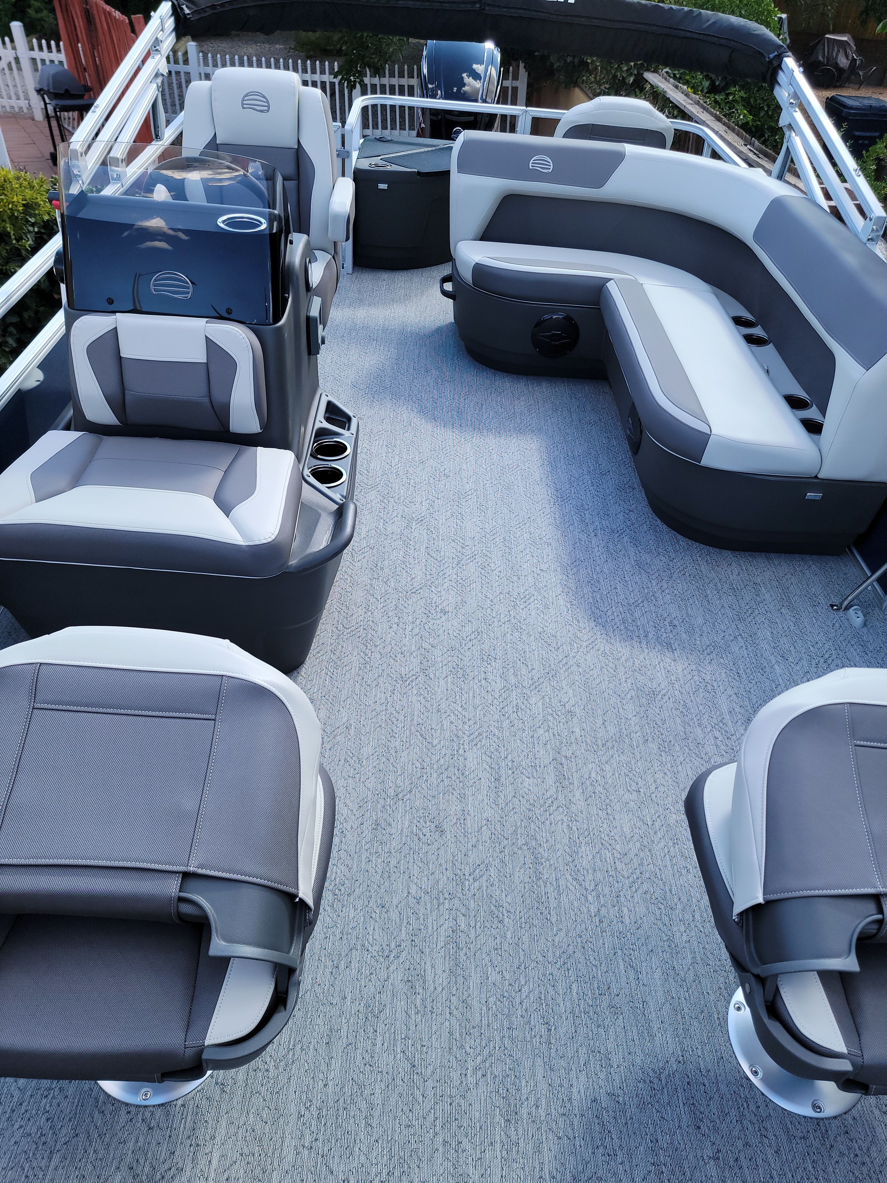 Interior view of a modern pontoon boat with gray seating and carpeted floor.