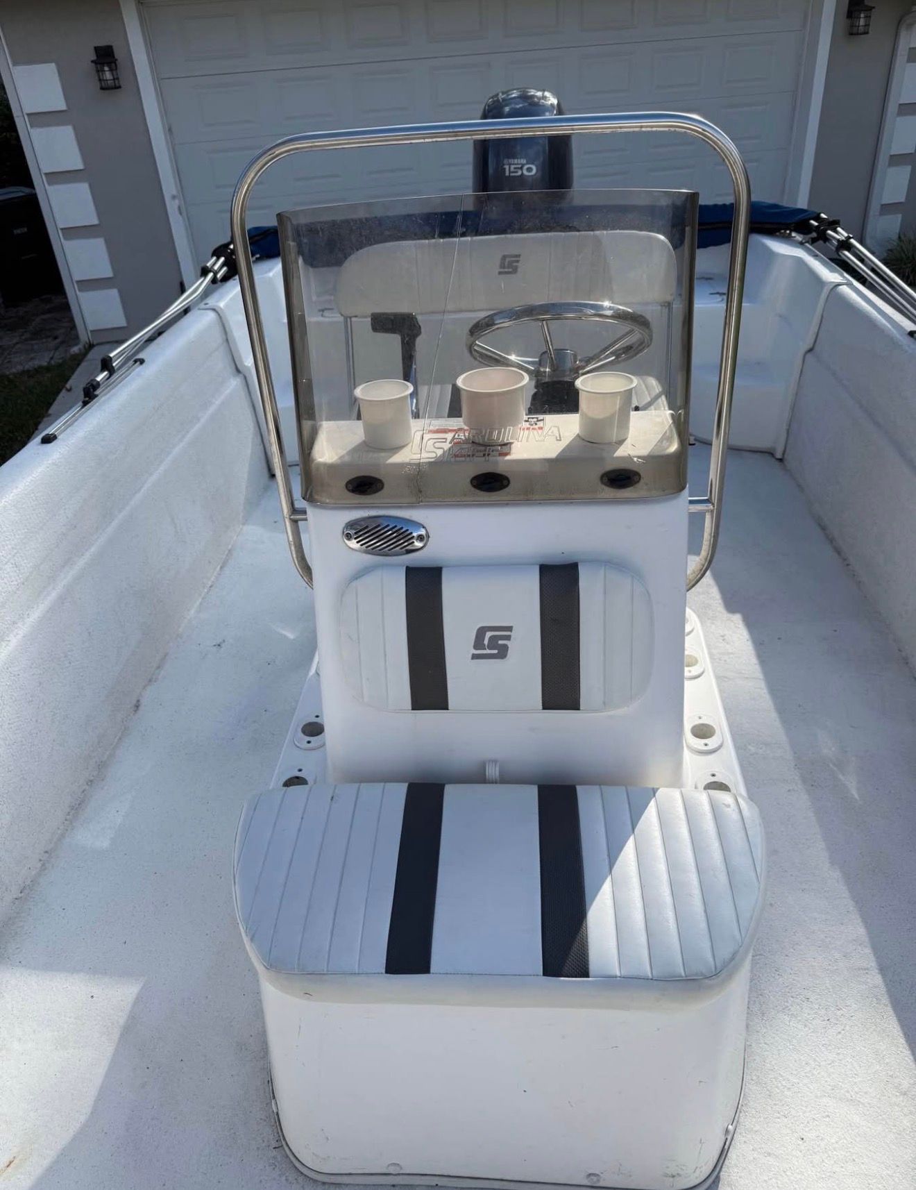The image shows the cockpit of a Carolina Skiff 258 DLV with a helm and cup holders.