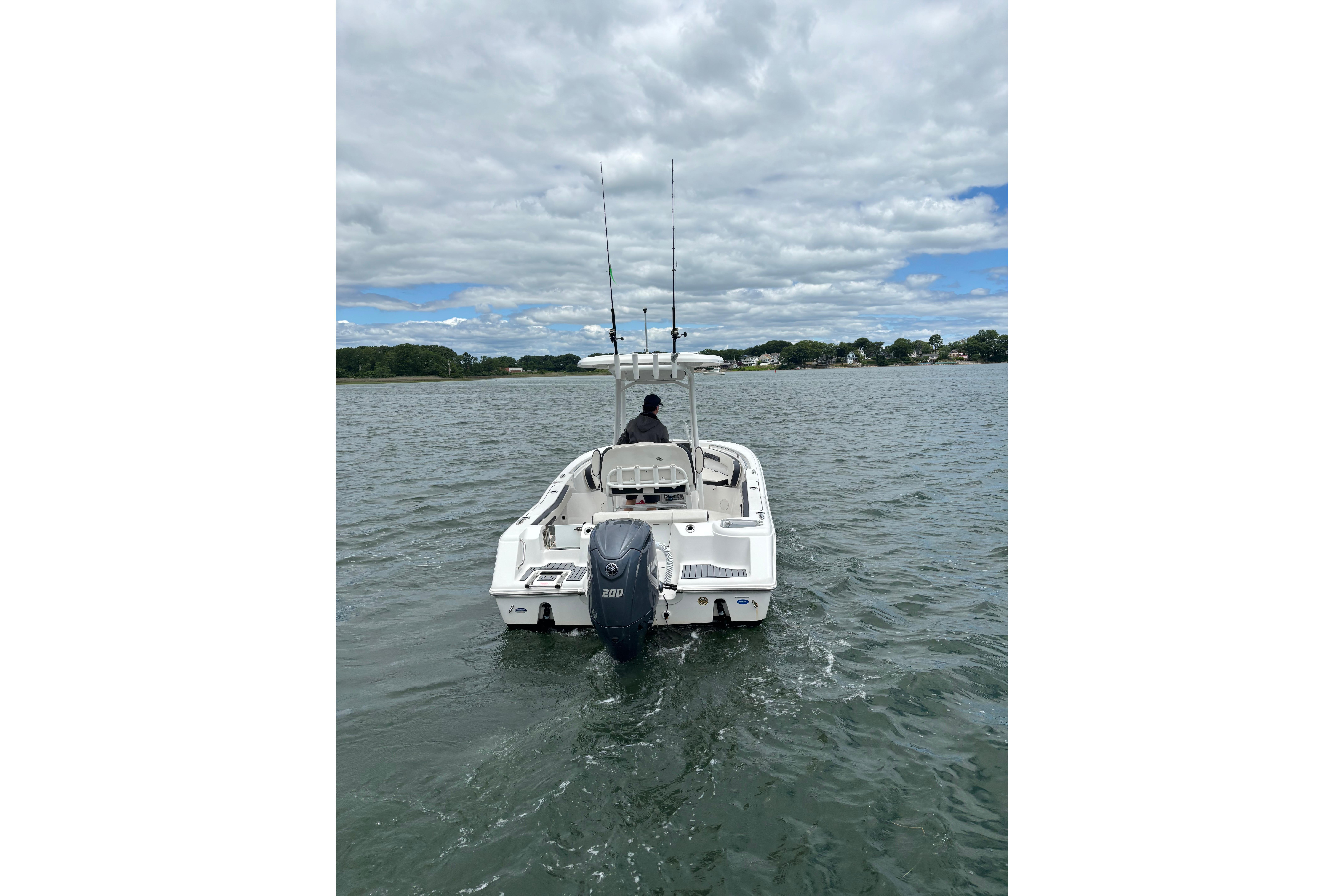 2024 Tidewater 220 CC Adventure boat cruising on a calm lake under a cloudy sky.