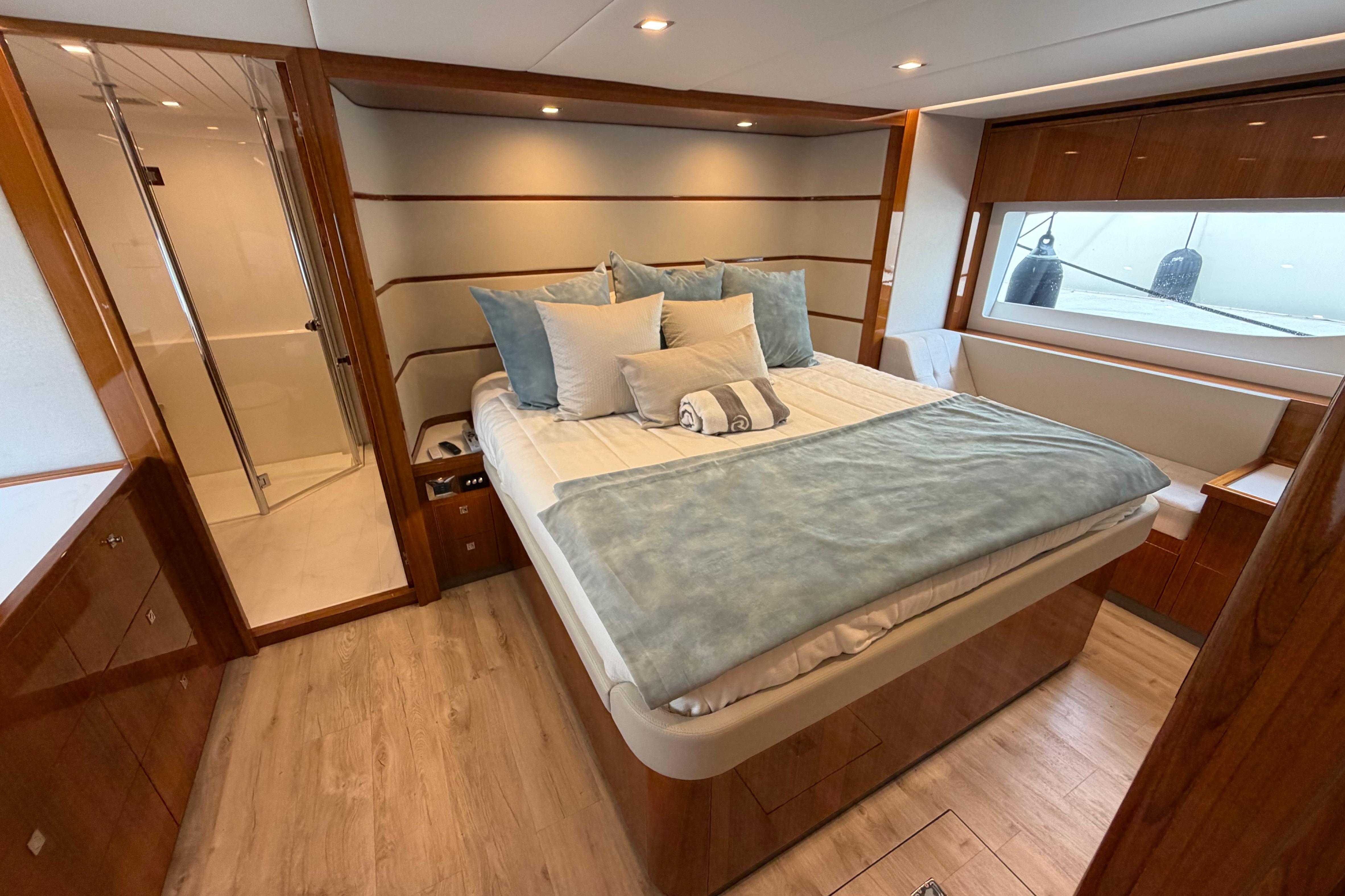 Luxurious bedroom interior of 2023 Riviera 645 SUV yacht with elegant wood finishes.
