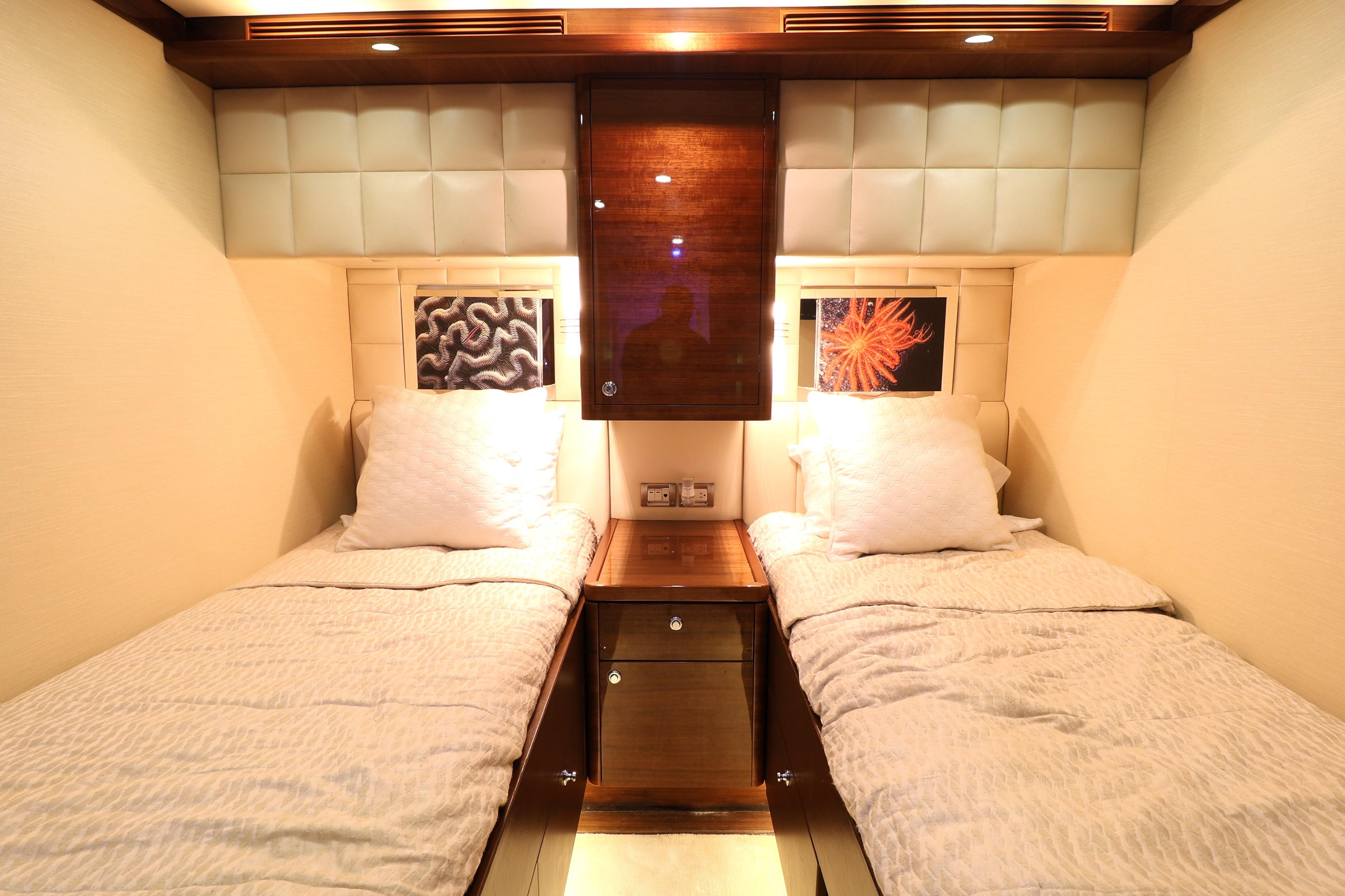 Luxurious twin cabin interior on 2013 Cheoy Lee Bravo yacht, featuring elegant bedding and ambient lighting.