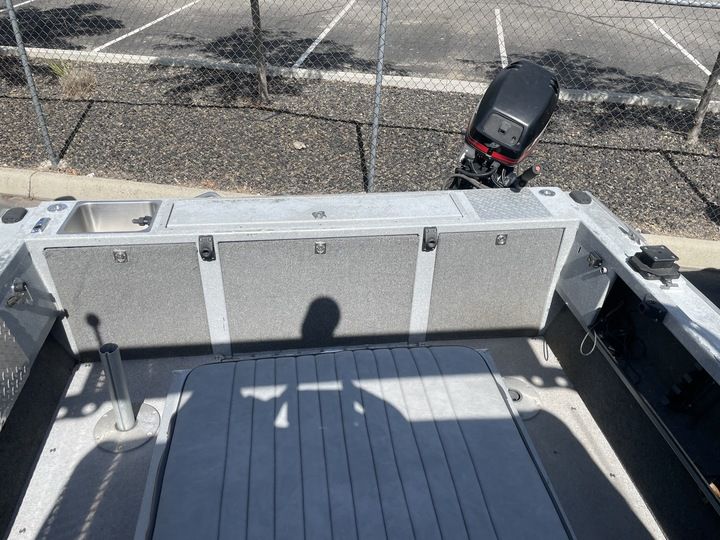The image shows the interior of a boat with gray upholstery and an outboard motor.