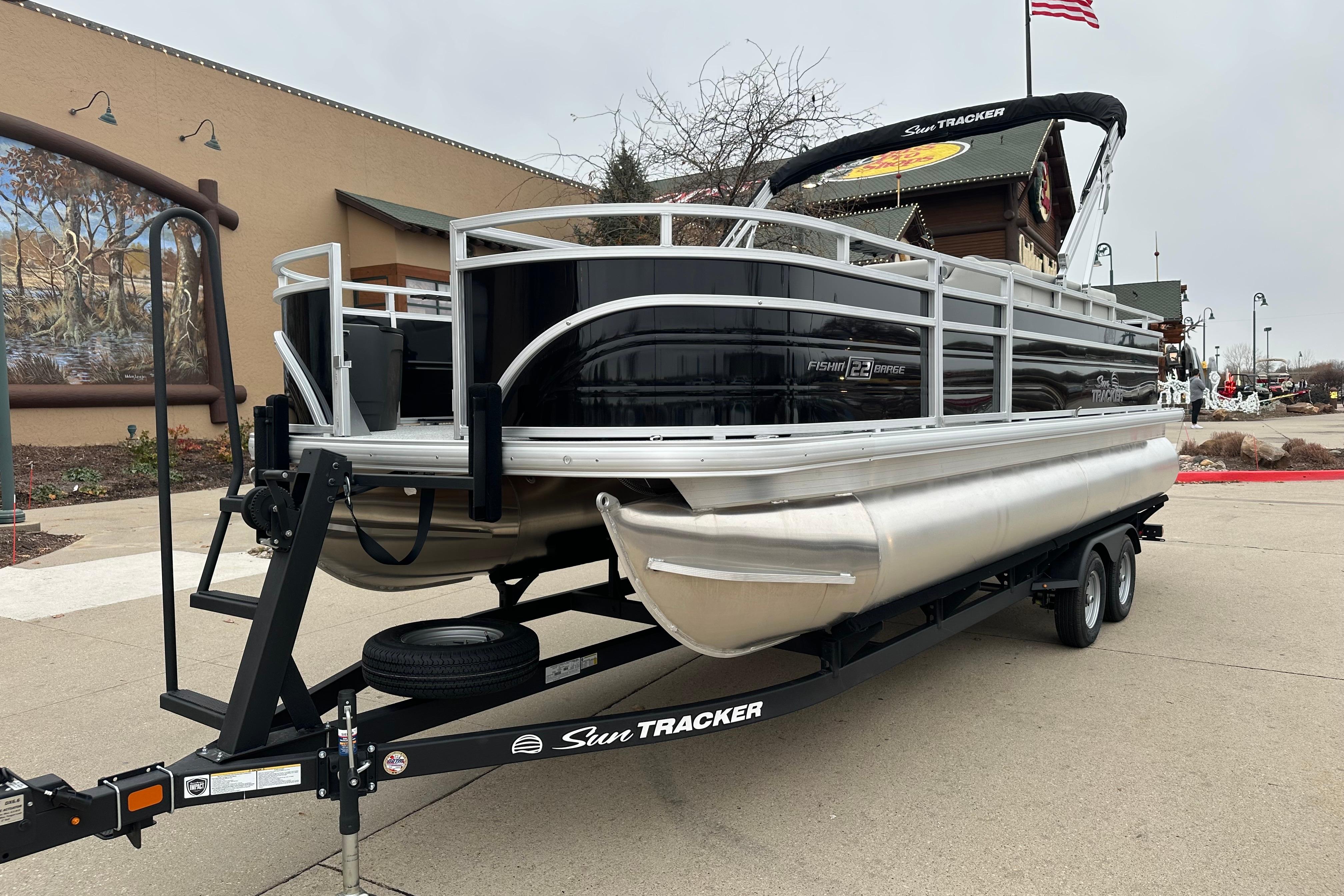 2026 Sun Tracker Fishin' Barge 22 DLX pontoon boat on trailer, outdoor setting.