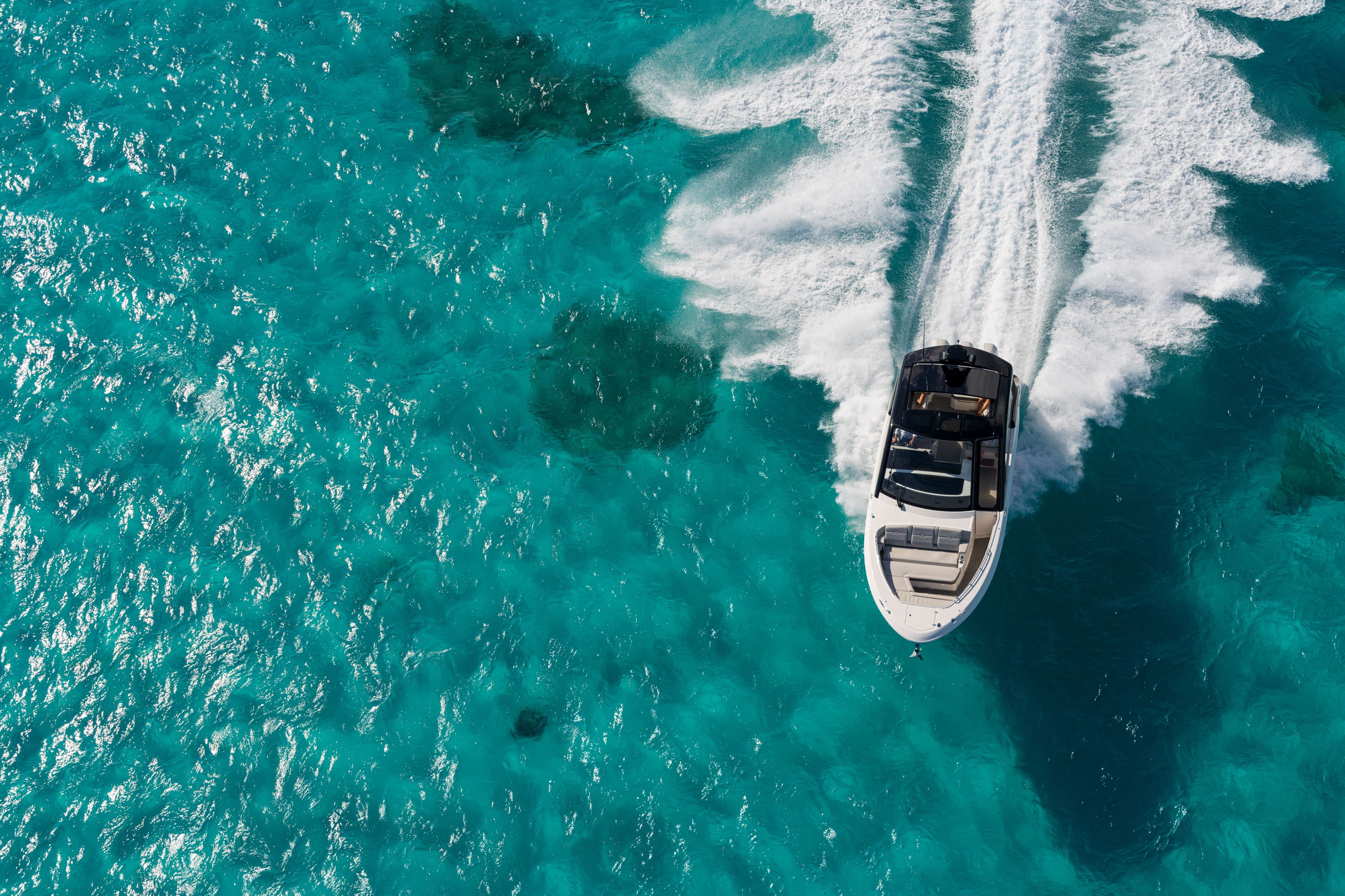 A 2026 Sea Ray Sundancer 370 Outboard speeds across turquoise water.