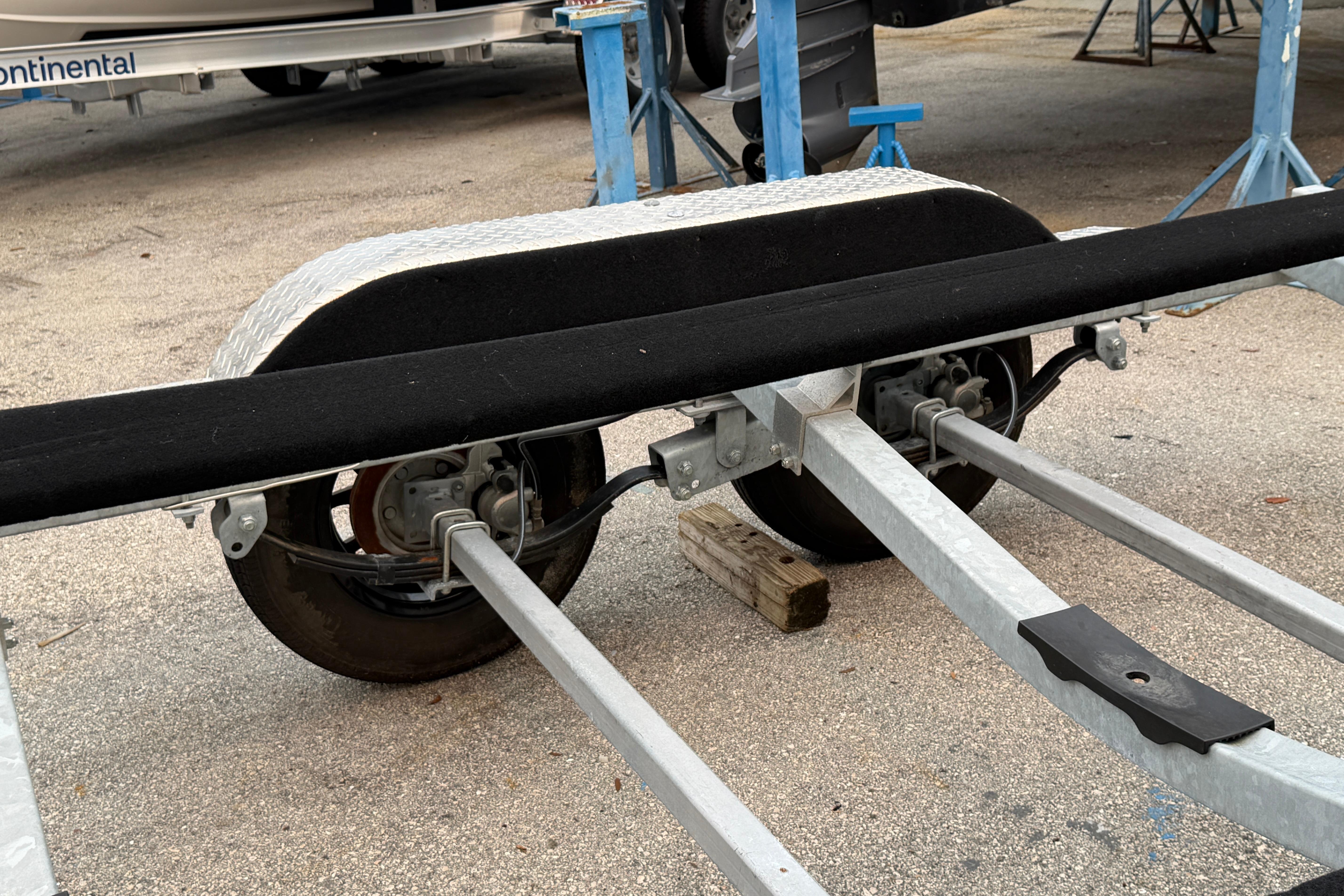 Trailer axle and wheels of 2024 SRT5000, parked on concrete surface.