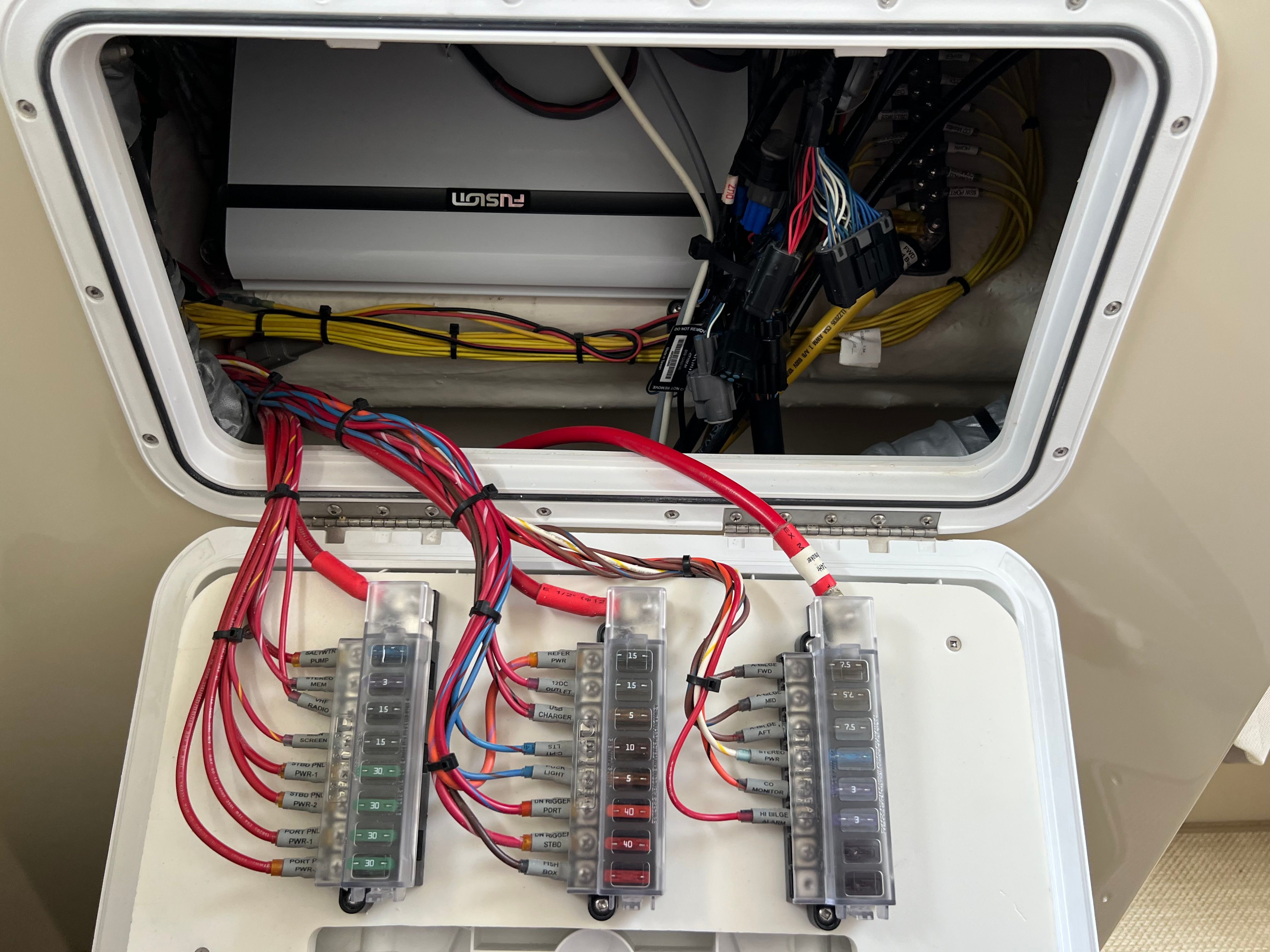 Electrical panel with colored wires and fuses inside a boat.
