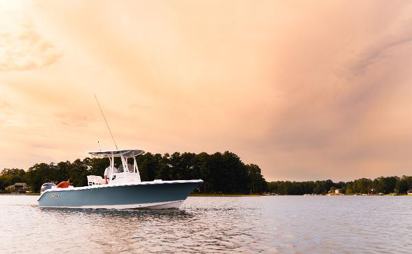 2024 Sea Hunt Ultra 234 boat cruising on a lake at sunset.