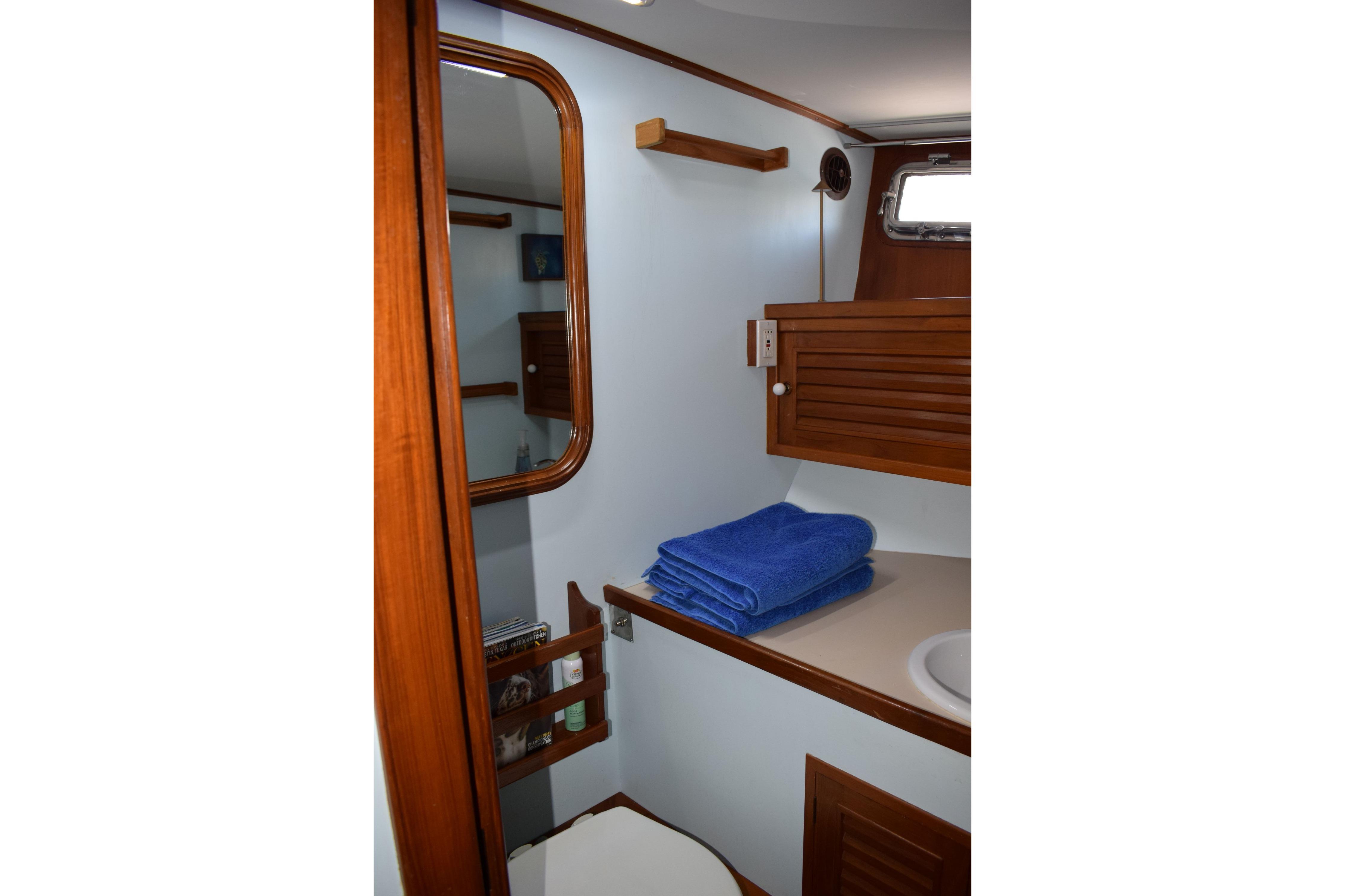 1980 Cheoy Lee 52 Motorsailer bathroom with wooden accents and blue towels.