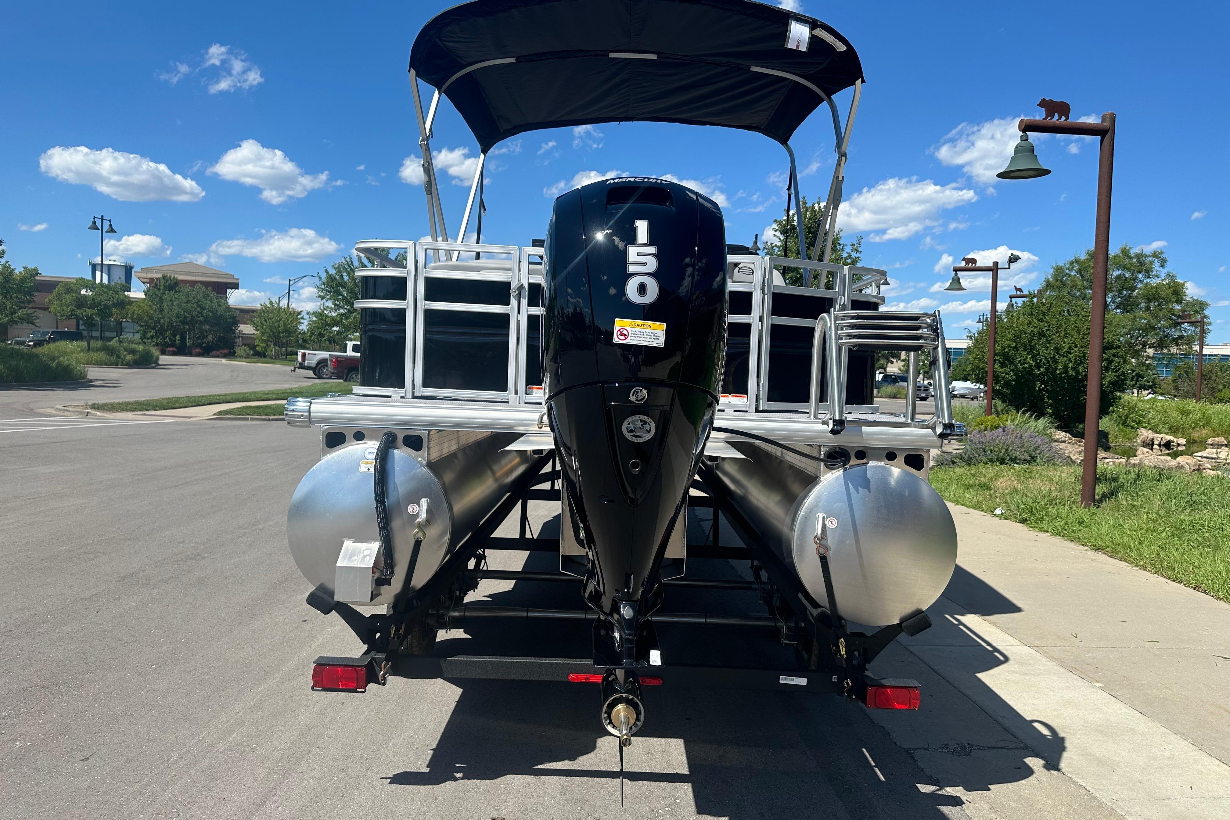 2026 Sun Tracker SportFish 22 DLX pontoon boat with 150 HP engine on a sunny day.