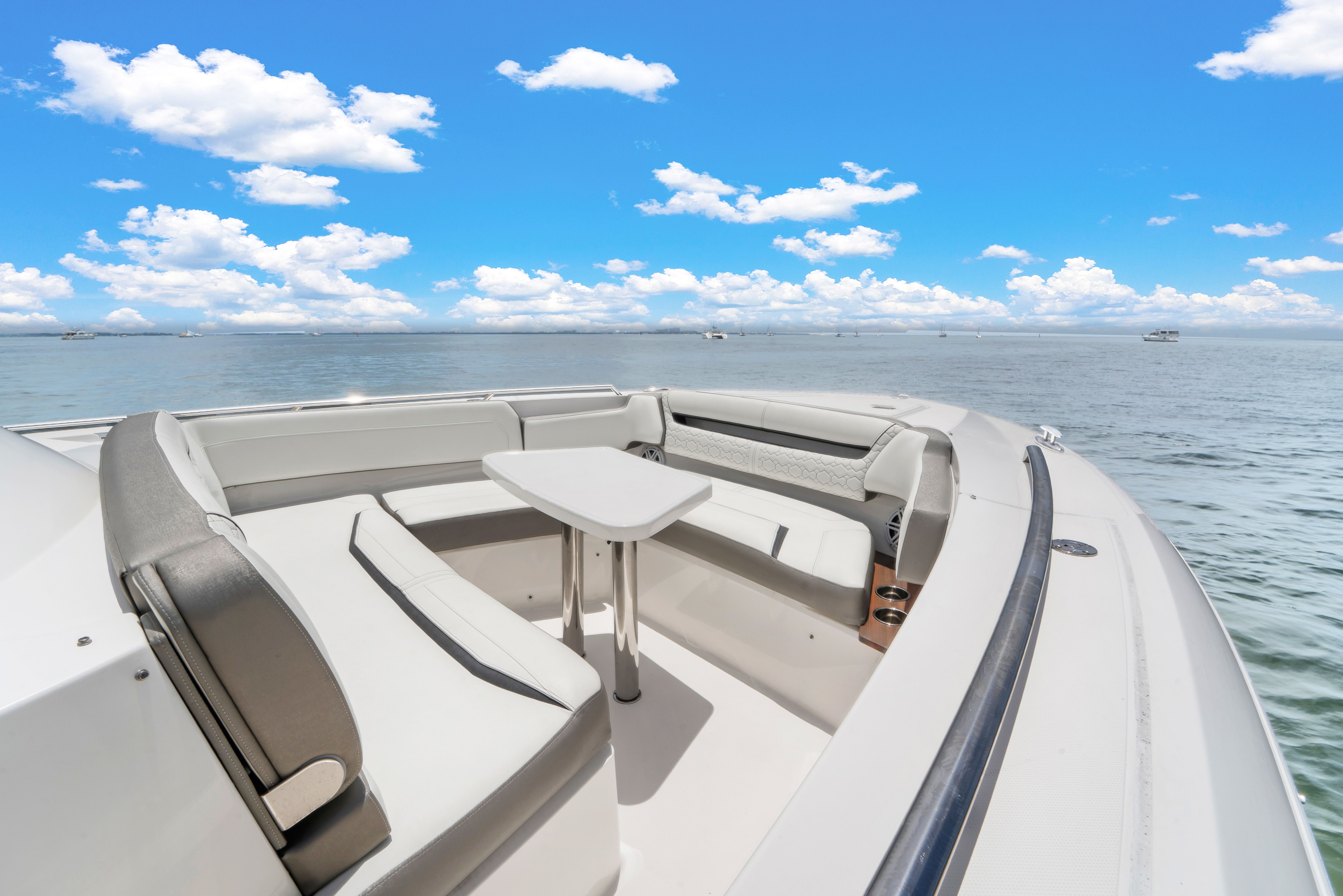 The image shows the bow of a 2023 Tiara Yachts 38 LS with seating area and table.