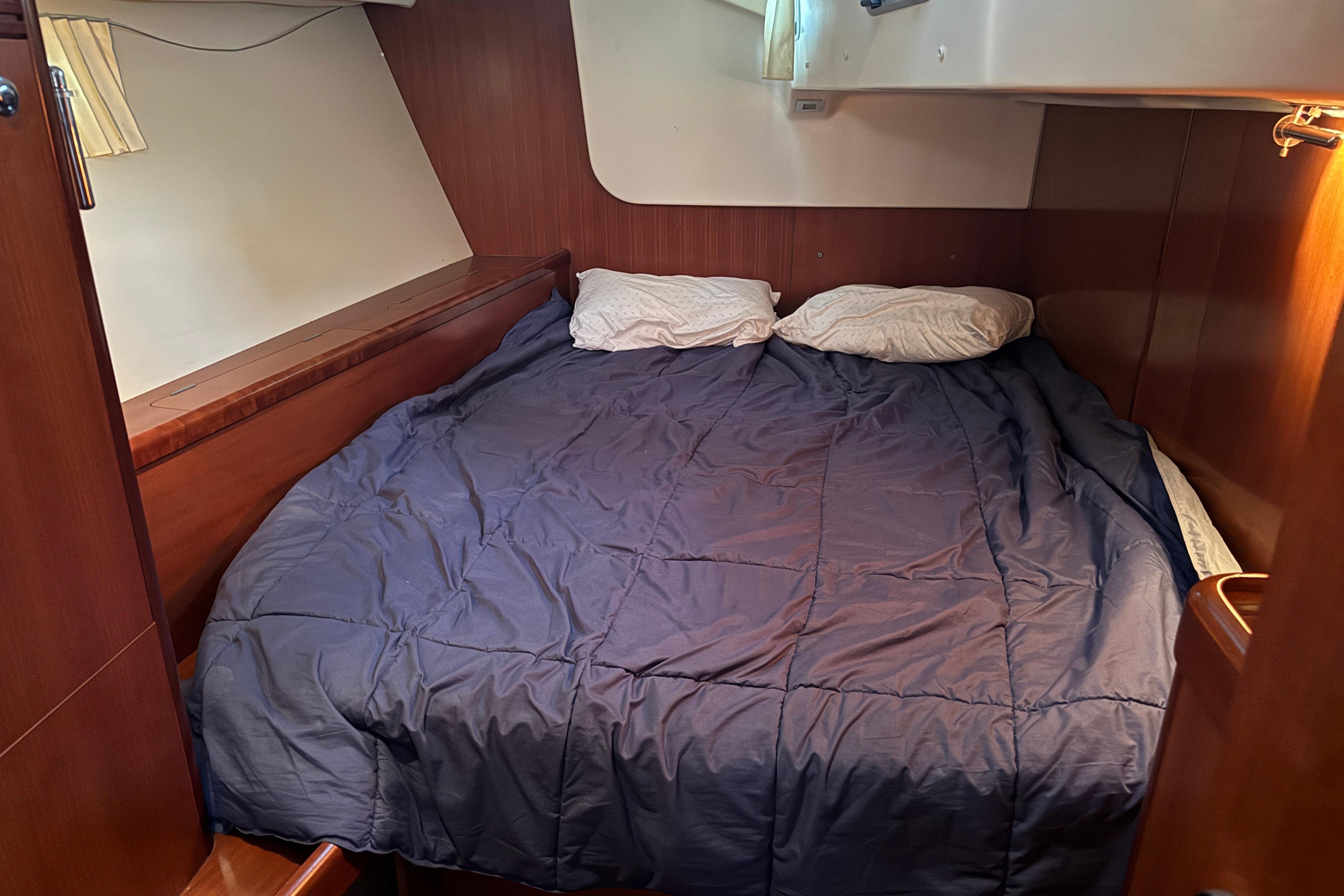 Cozy cabin interior of 2007 Beneteau 49 yacht with double bed and wooden finish.