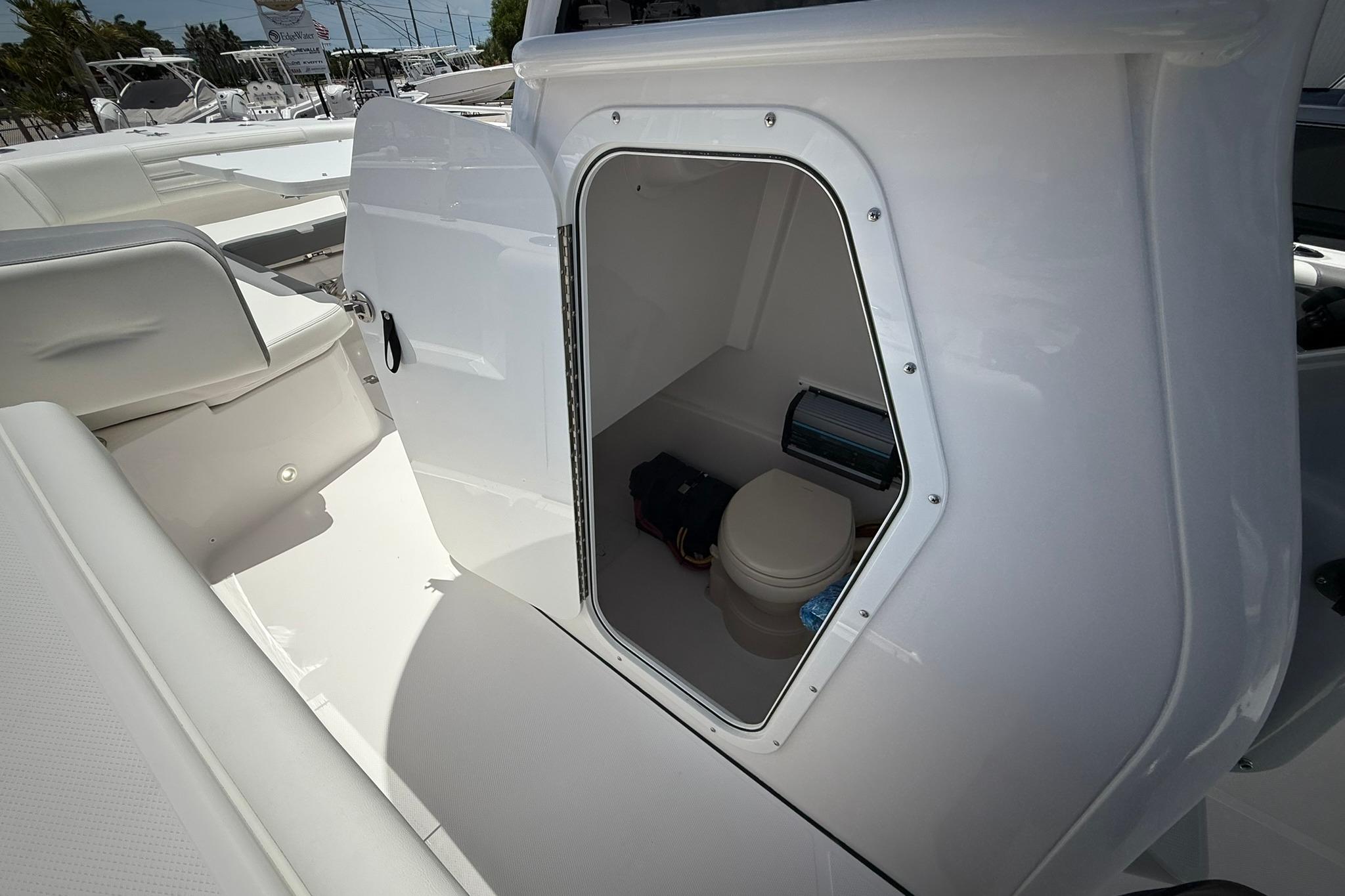 2026 Edgewater 250CC boat interior with open compartment showing a compact marine toilet.