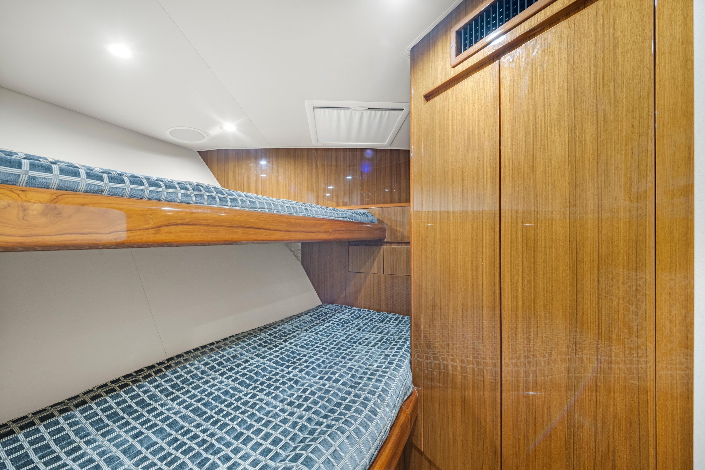 Interior of 2009 Viking 50 Convertible yacht with wooden bunk beds and blue checkered bedding.