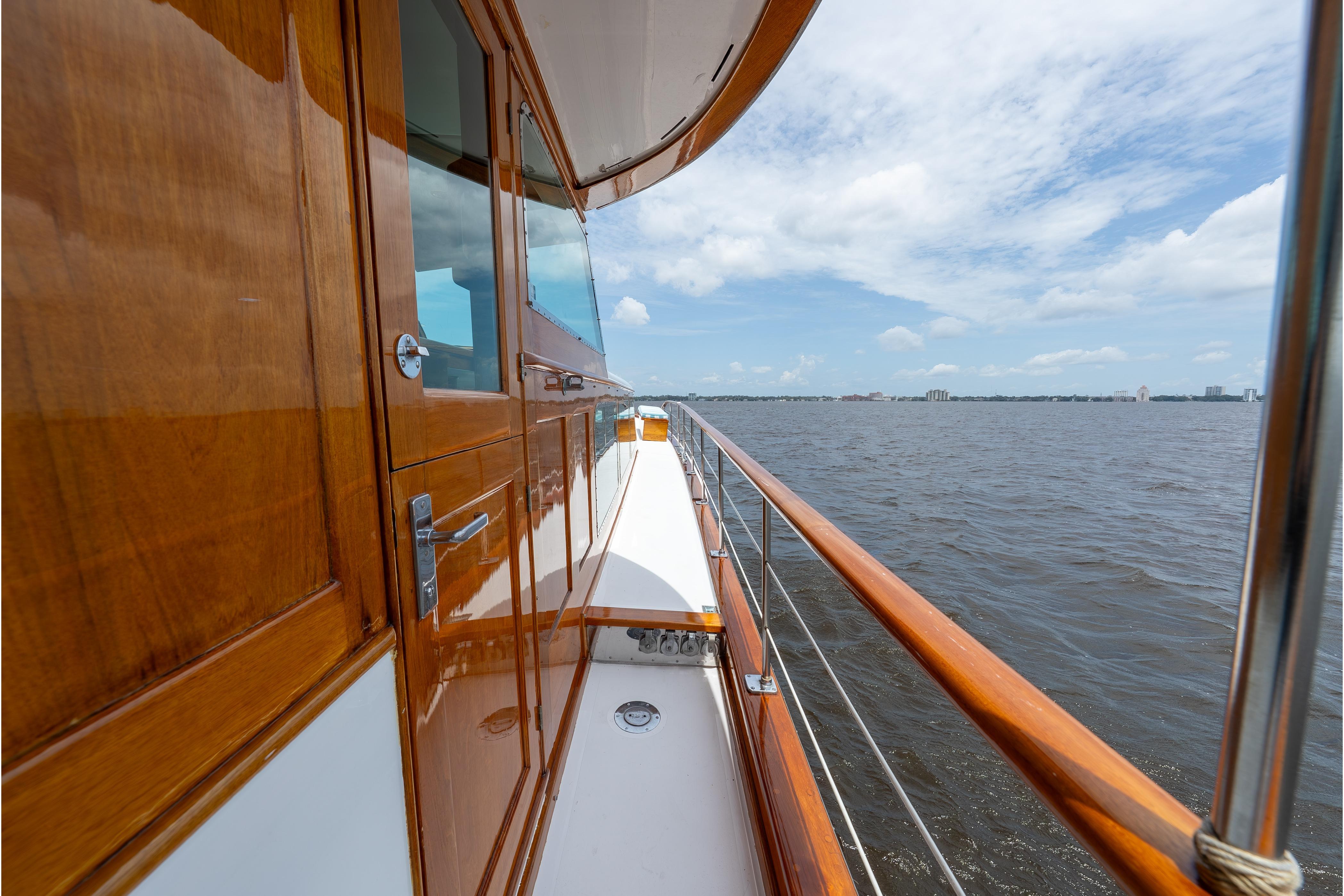 Side view of a 1963 Trumpy Classic yacht with polished wood finish on open water.