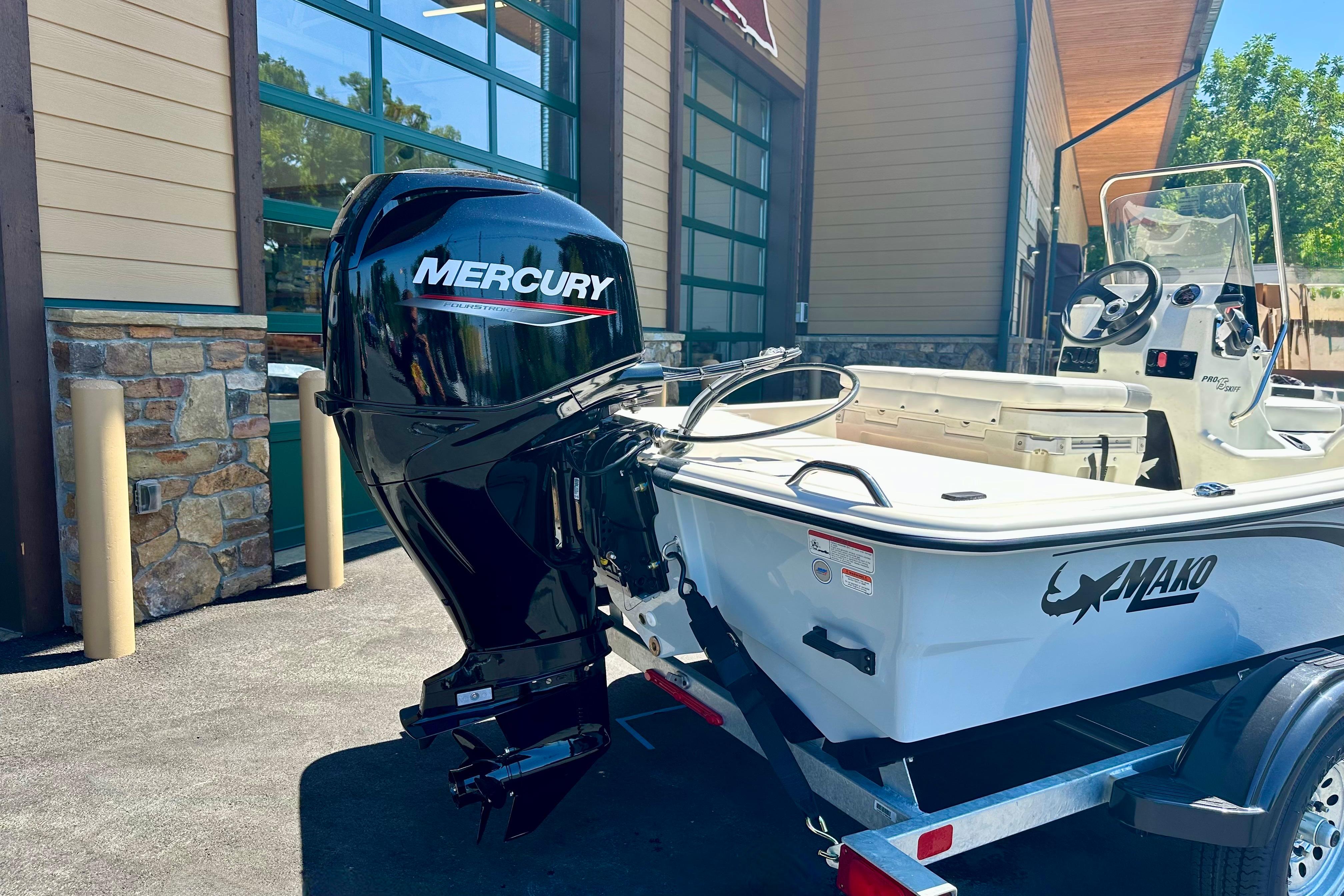 2026 Mako Pro Skiff 15 CC boat with Mercury outboard motor, parked outside a building.
