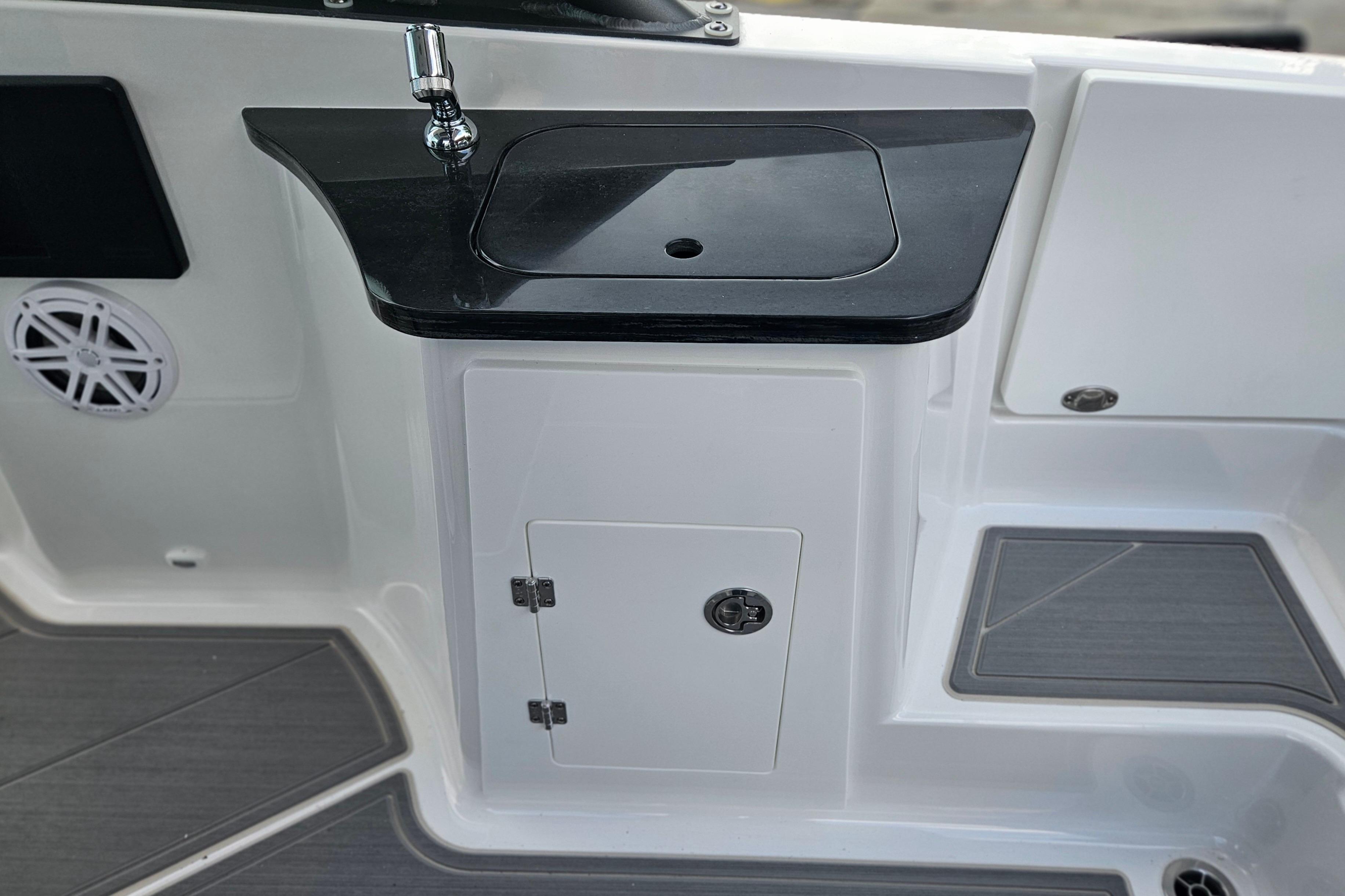 2026 Monterey Elite 27 OB boat sink and storage area with sleek black countertop.