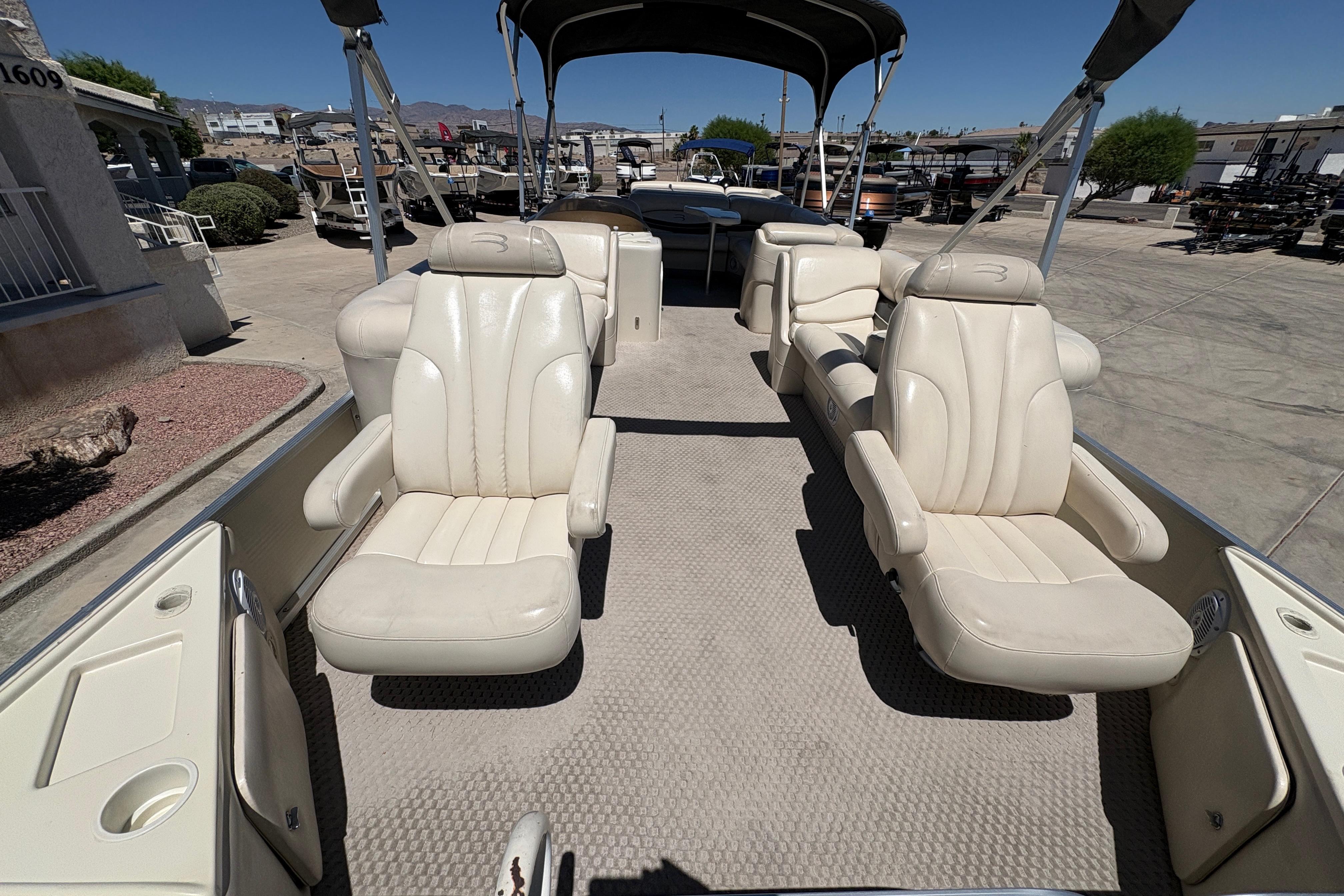 2005 Bennington 2575RFS I/O boat interior with plush seating and canopy in a marina setting.