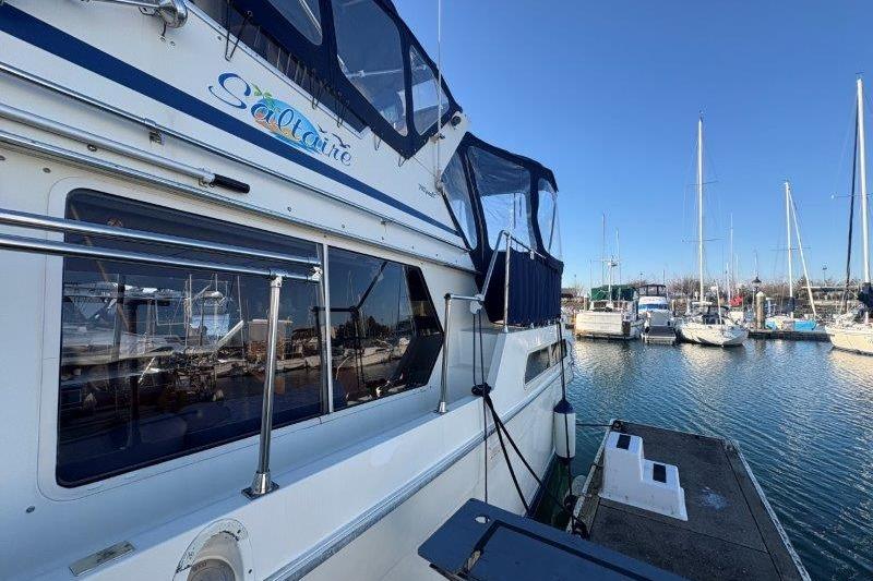 1987 Tollycraft 34 Sundeck Motor Yacht docked at marina under clear blue sky.