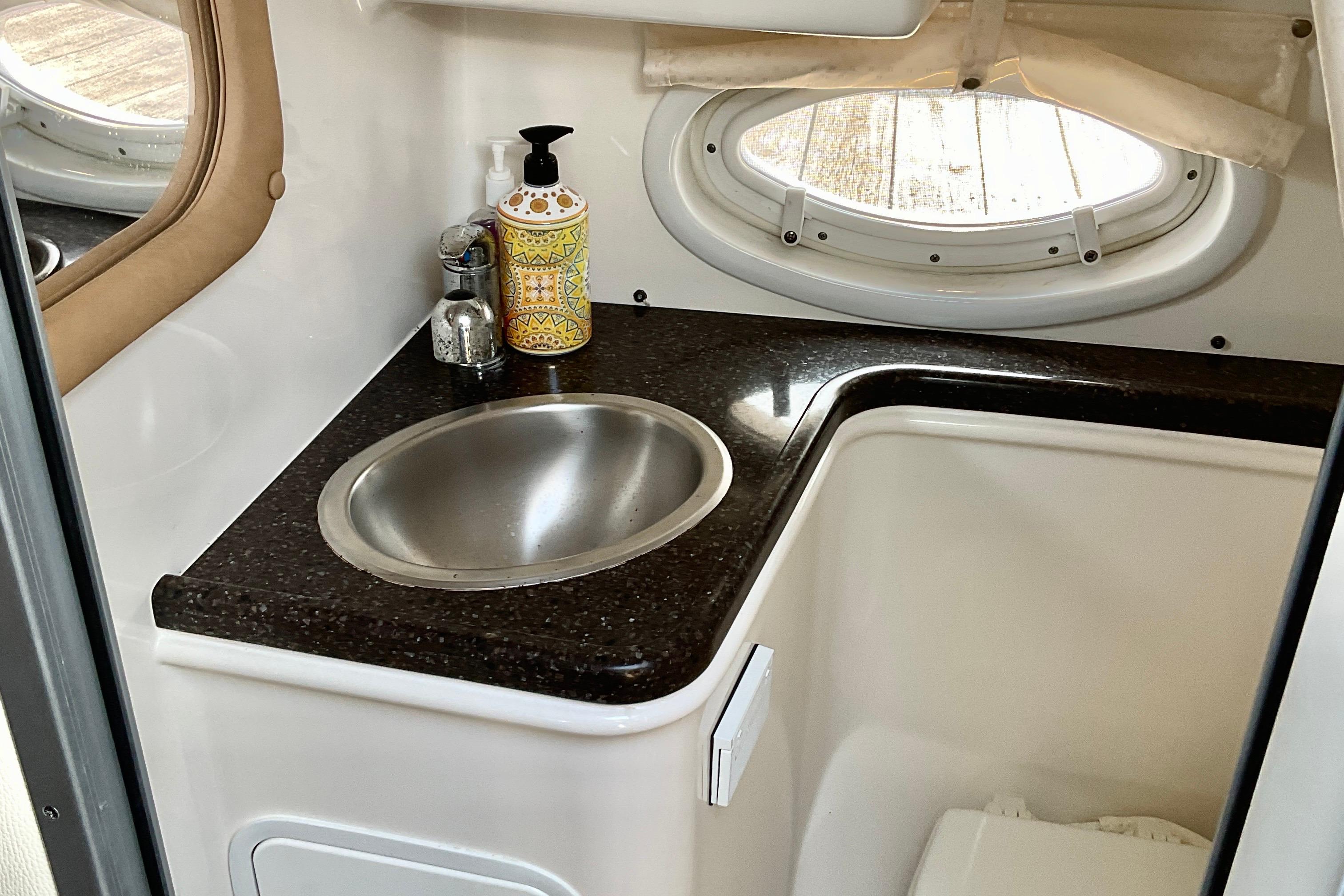 2013 Rinker 290 Express Cruiser bathroom with sink, countertop, and porthole window.