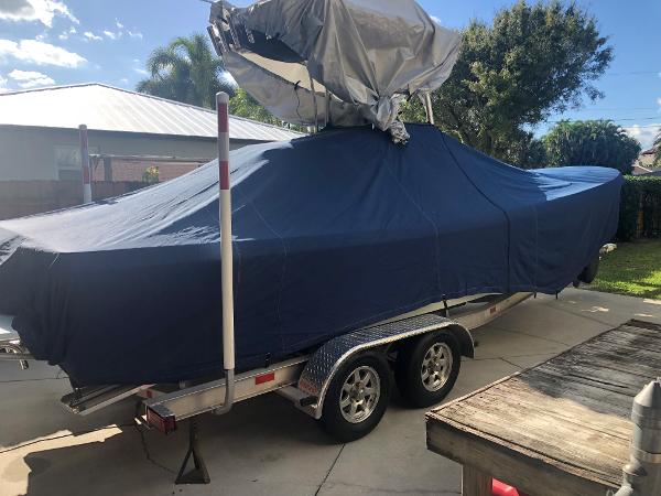 A 2011 Andros 26 Tarpon boat covered on a trailer in a yard.