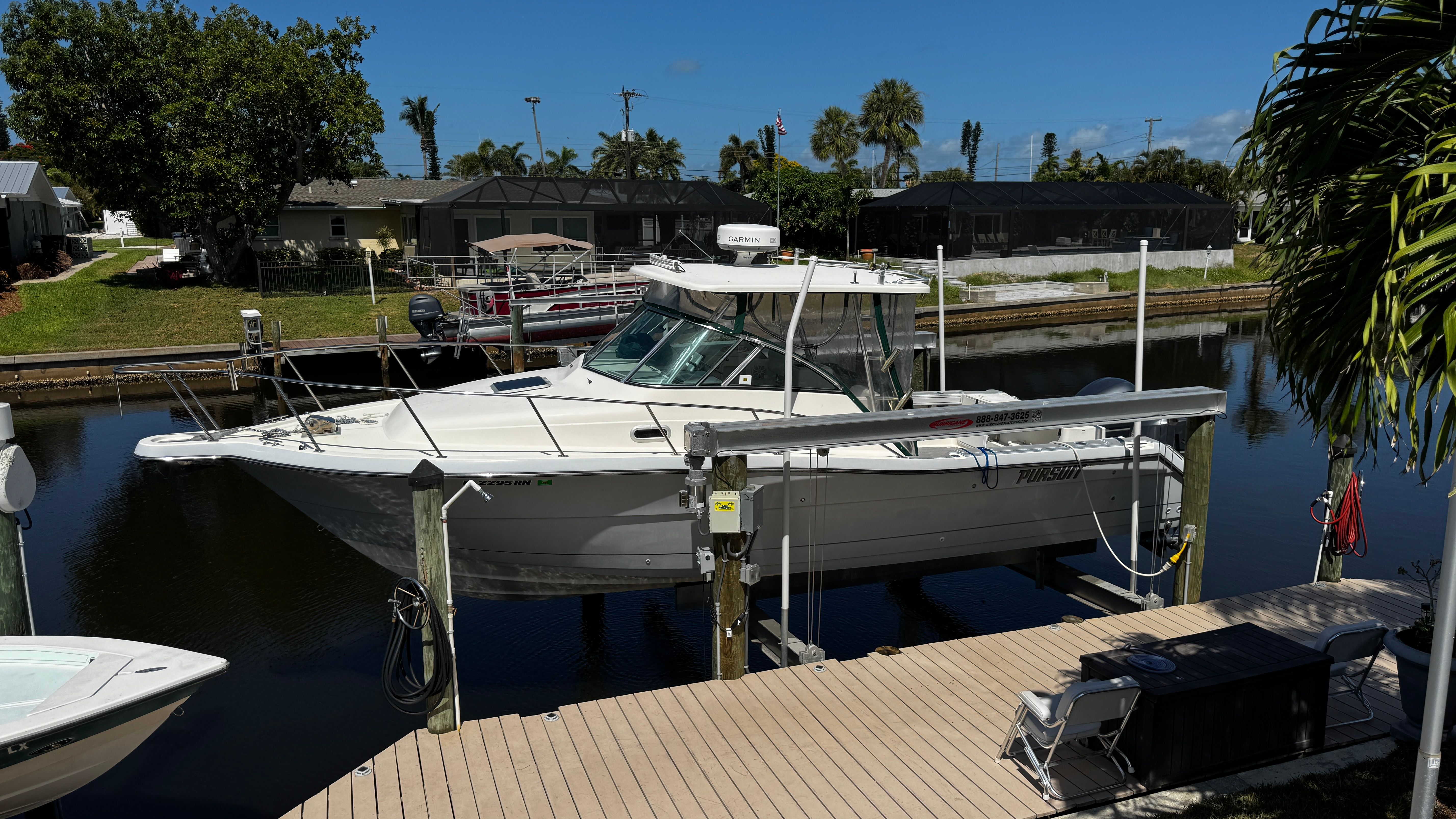 2003 Pursuit 3070 on a boat lift by a calm canal.