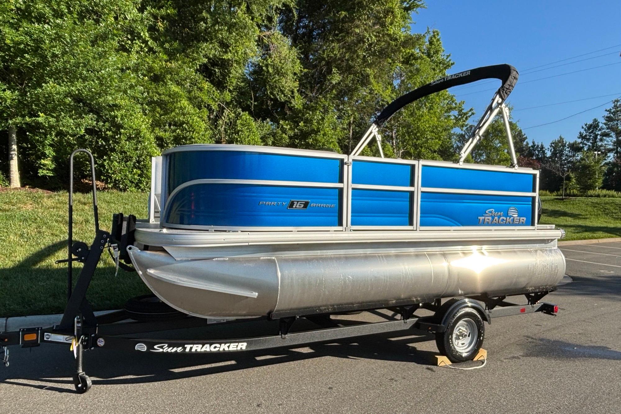 2026 Sun Tracker Party Barge 16 DLX pontoon boat on trailer, parked outdoors.