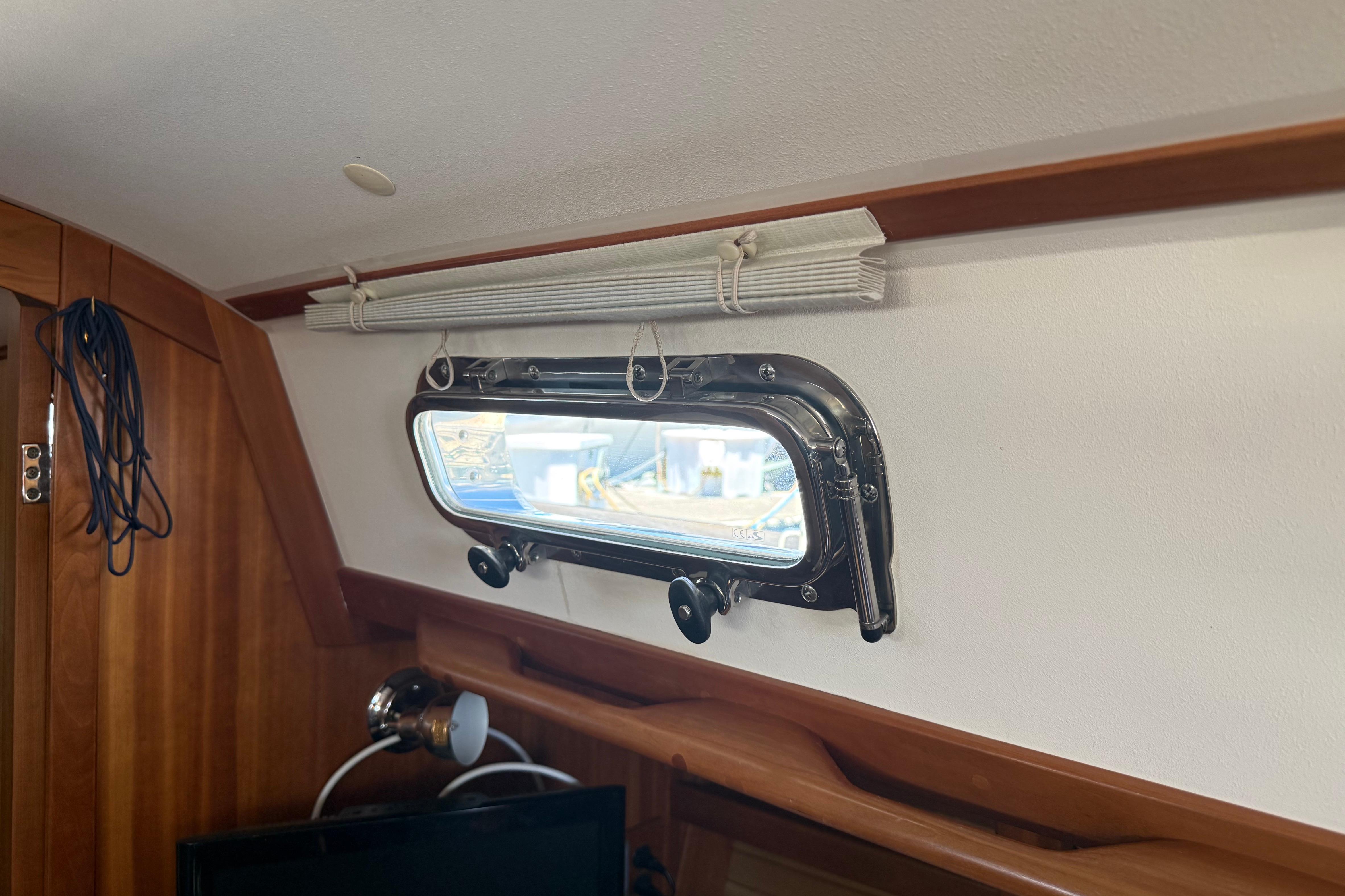 Interior of 2004 Sabre 386 yacht showing a porthole and wooden paneling.