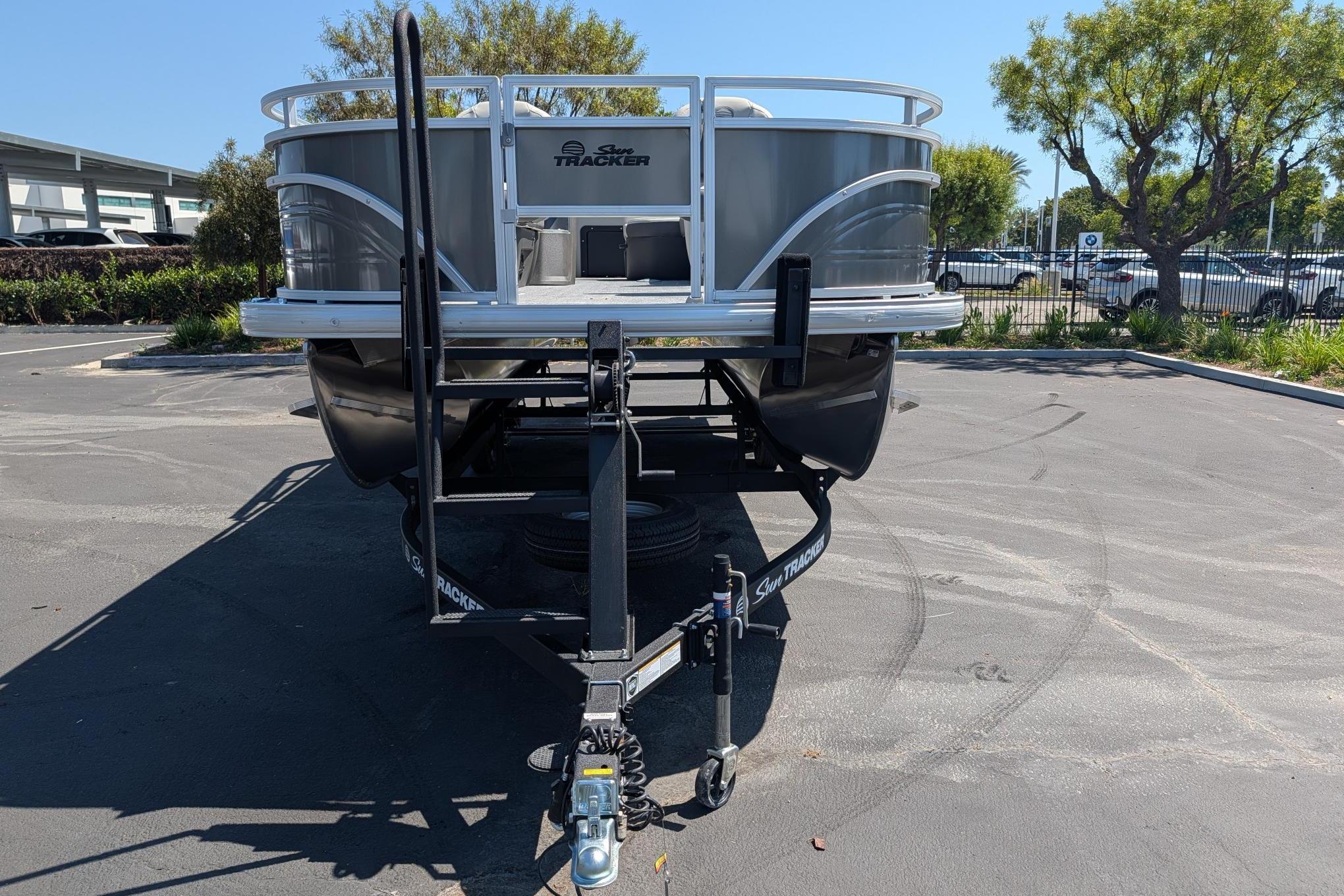 2026 Sun Tracker Fishin' Barge 22 DLX on trailer in parking lot.