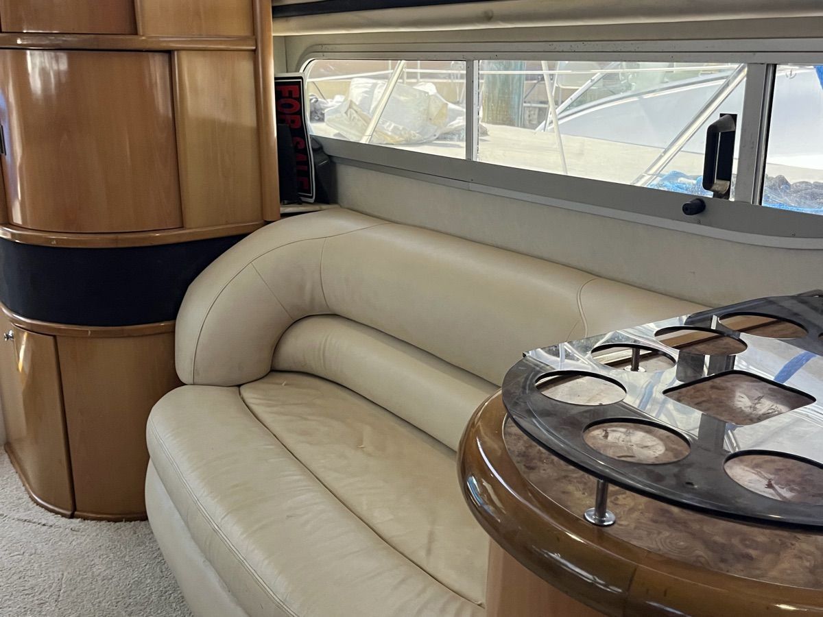 The image shows the interior of a 1999 Sealine F44 with a cream leather couch and round table.