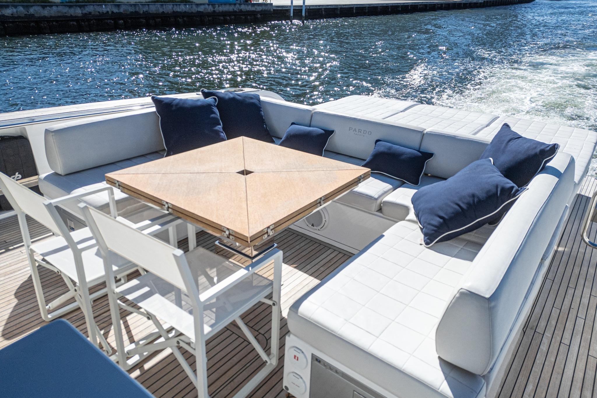 Luxurious seating area on 2019 Pardo Yachts P50, featuring elegant cushions and a wooden table.