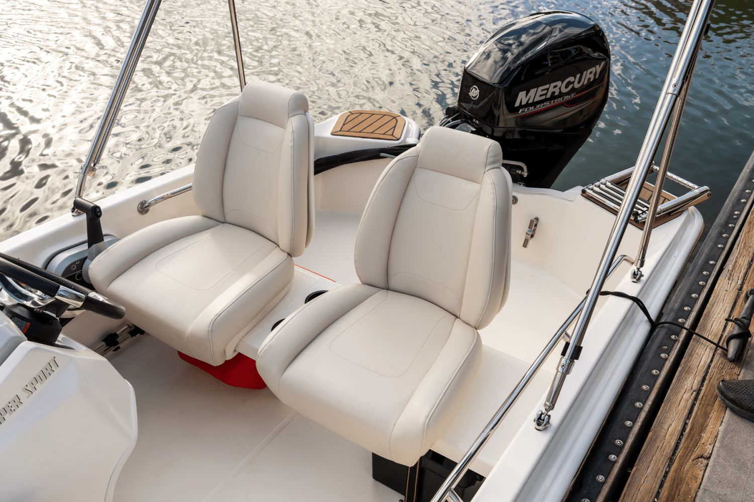 Two white seats on a Boston Whaler 130 Super Sport boat, with a Mercury outboard motor.