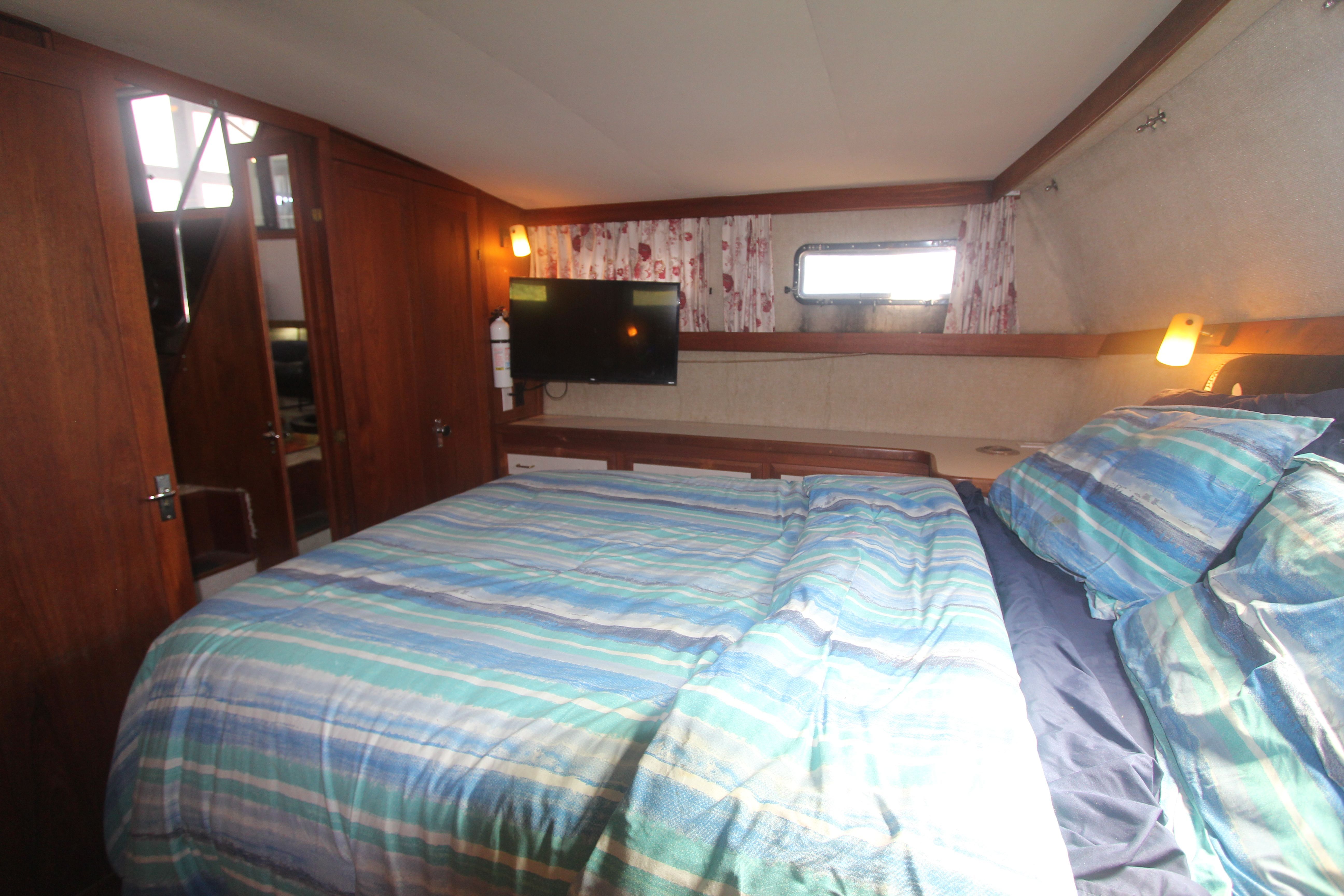 Interior of a 1988 Carver 3607 Aft Cabin Motor Yacht with cozy bed and TV.