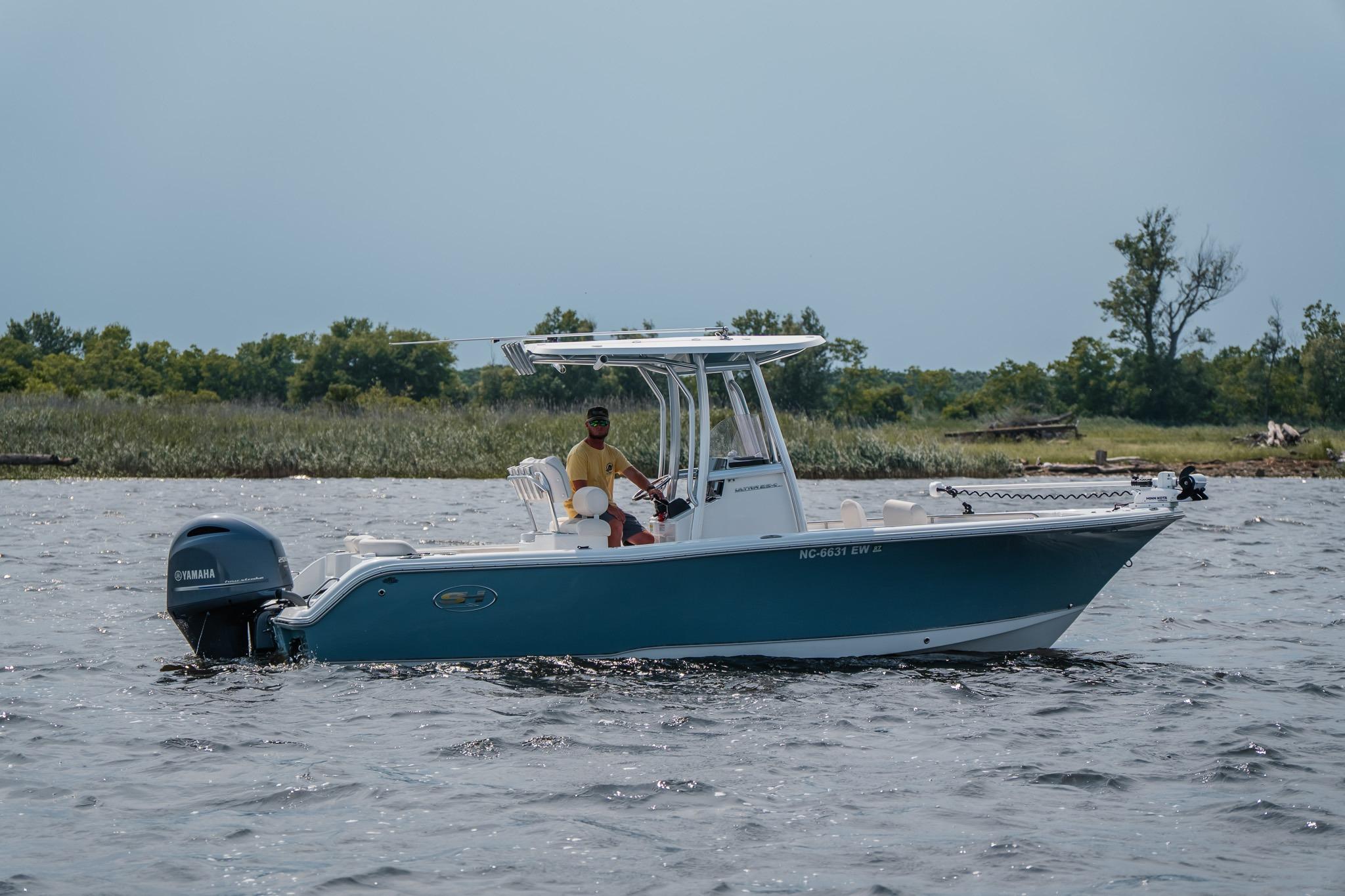 2022 Sea Hunt Ultra 229 boat cruising on a lake with lush greenery in the background.