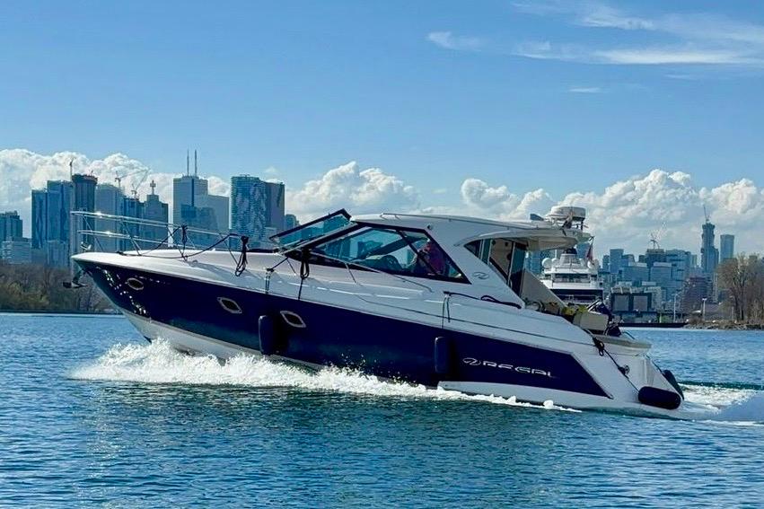 2012 Regal 42 Sport Coupe cruising on water with city skyline backdrop.