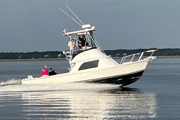 1976 Bertram Flybridge Cruiser on calm water, with passengers enjoying the ride.