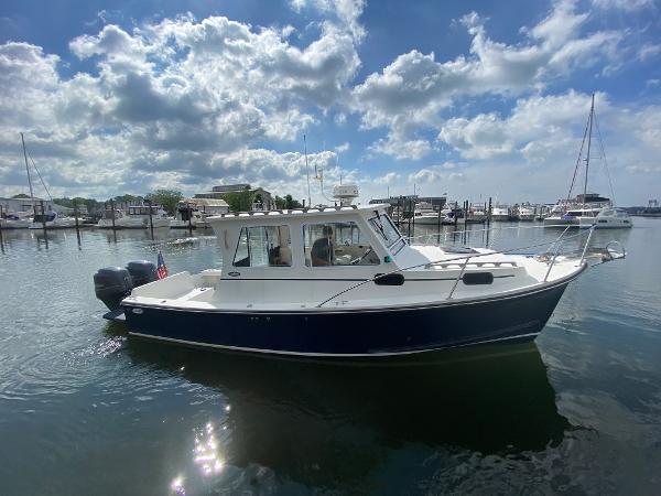 A 2015 Eastern 27 Islander boat on calm water, surrounded by other boats in the harbor.