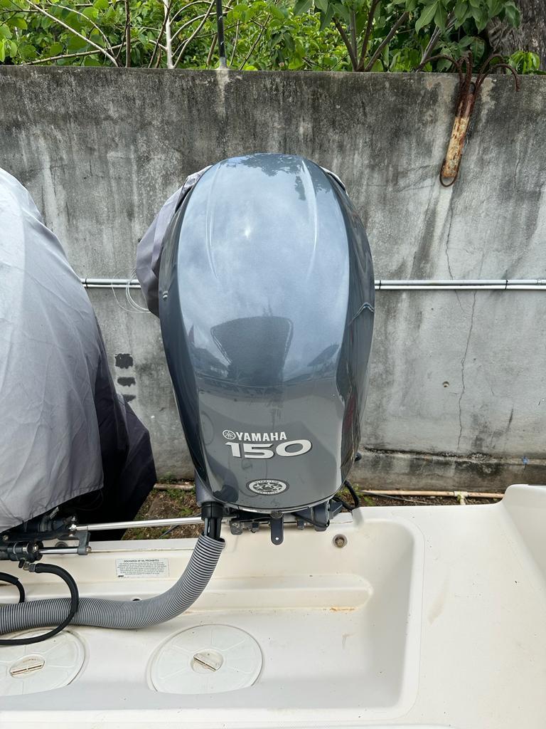 Yamaha 150 outboard motor on a 2012 Pursuit 255 boat, parked near a concrete wall.