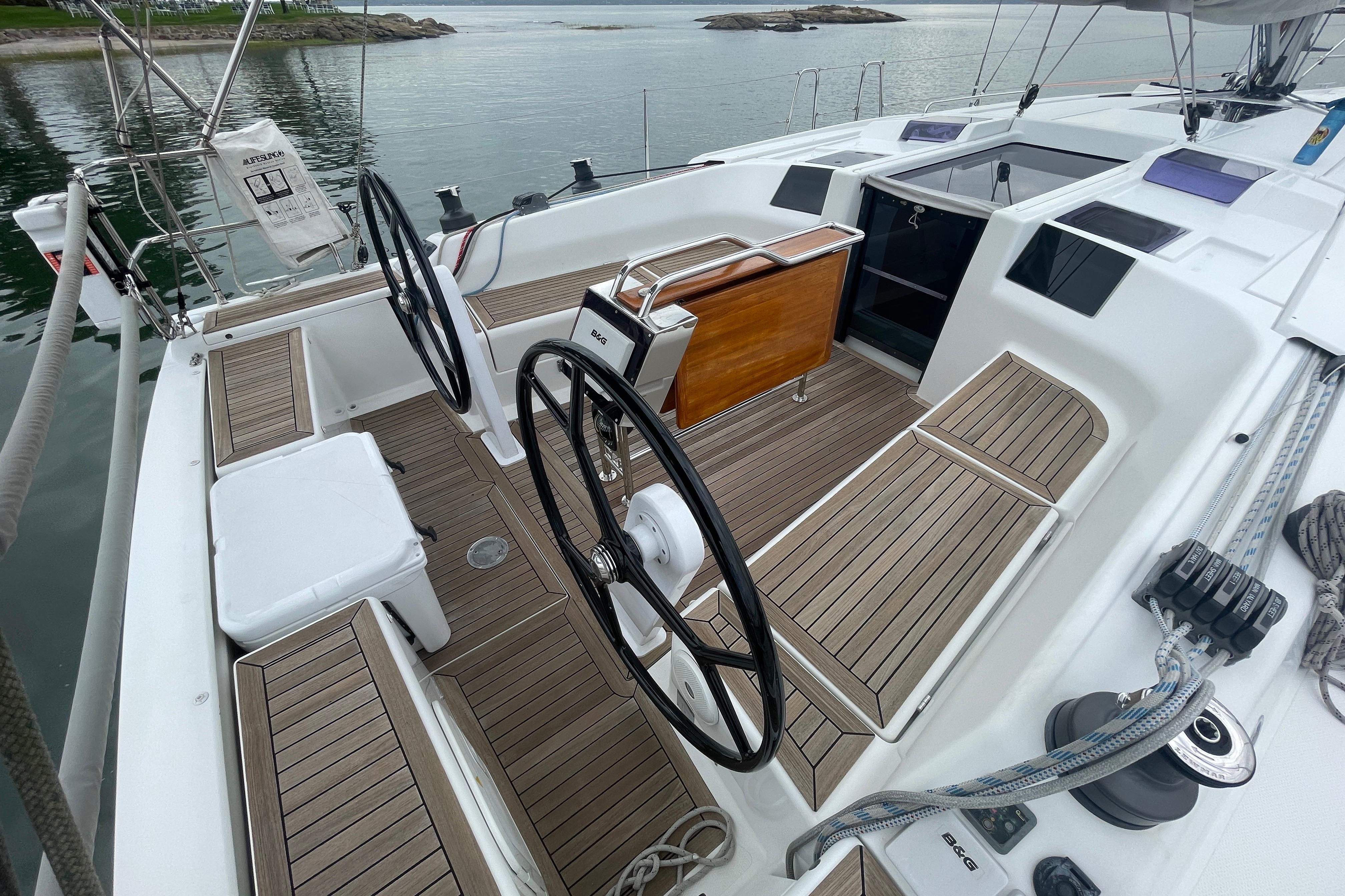 2014 Hanse 415 yacht cockpit with dual steering wheels and teak flooring, docked by calm waters.