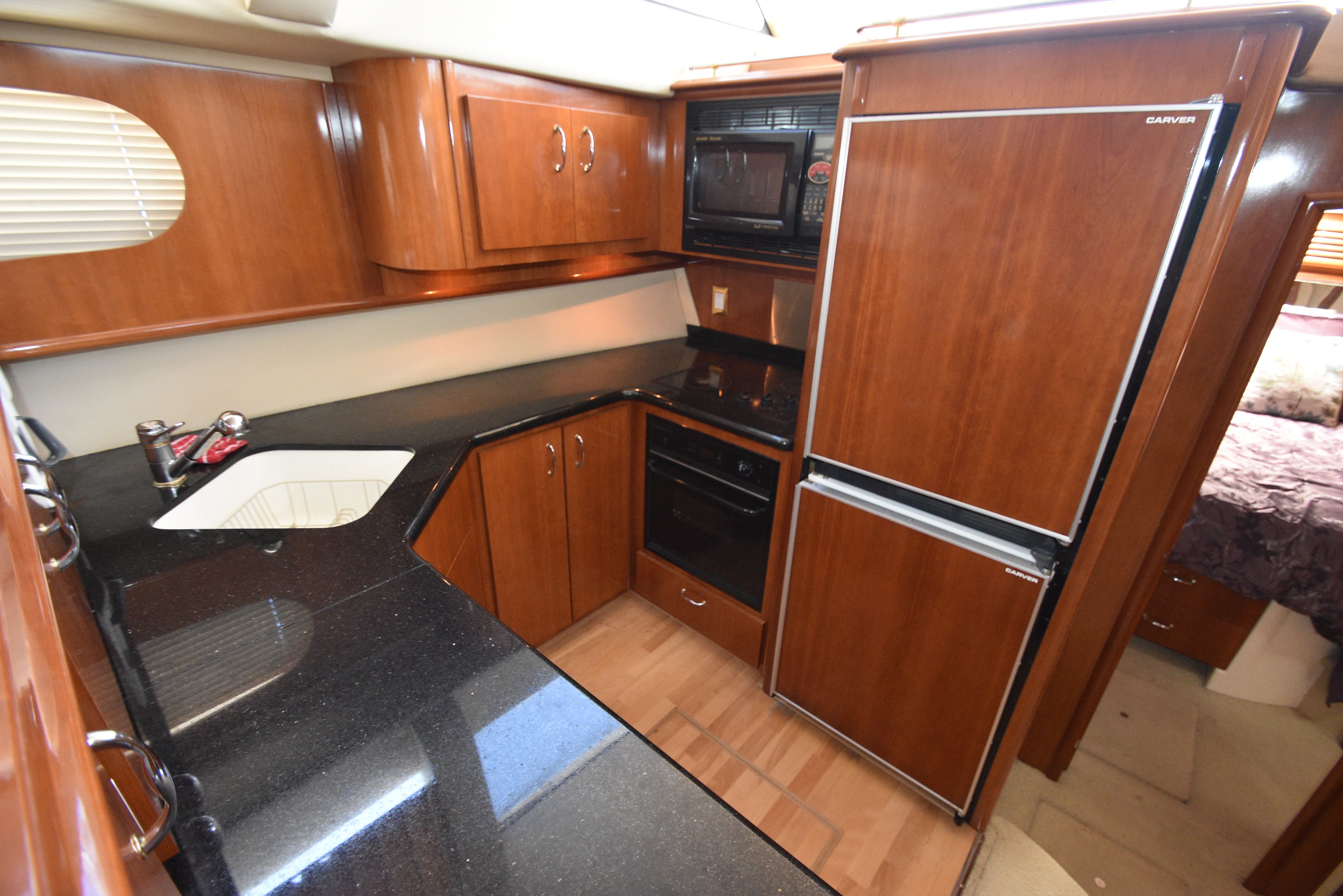 The 2004 Carver 466 Motor Yacht's kitchen features wood cabinets, a refrigerator, and a stove.