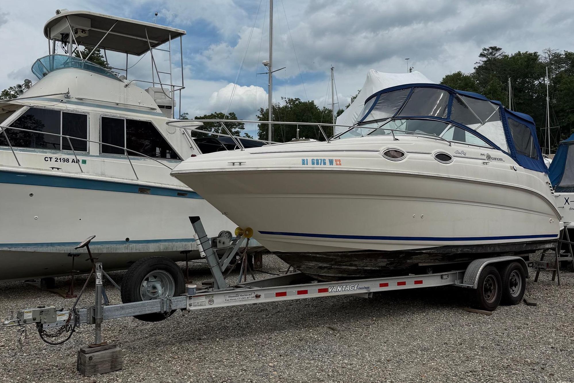 A Sea Ray 240 Sundancer boat on a trailer, surrounded by other boats in the harbor.