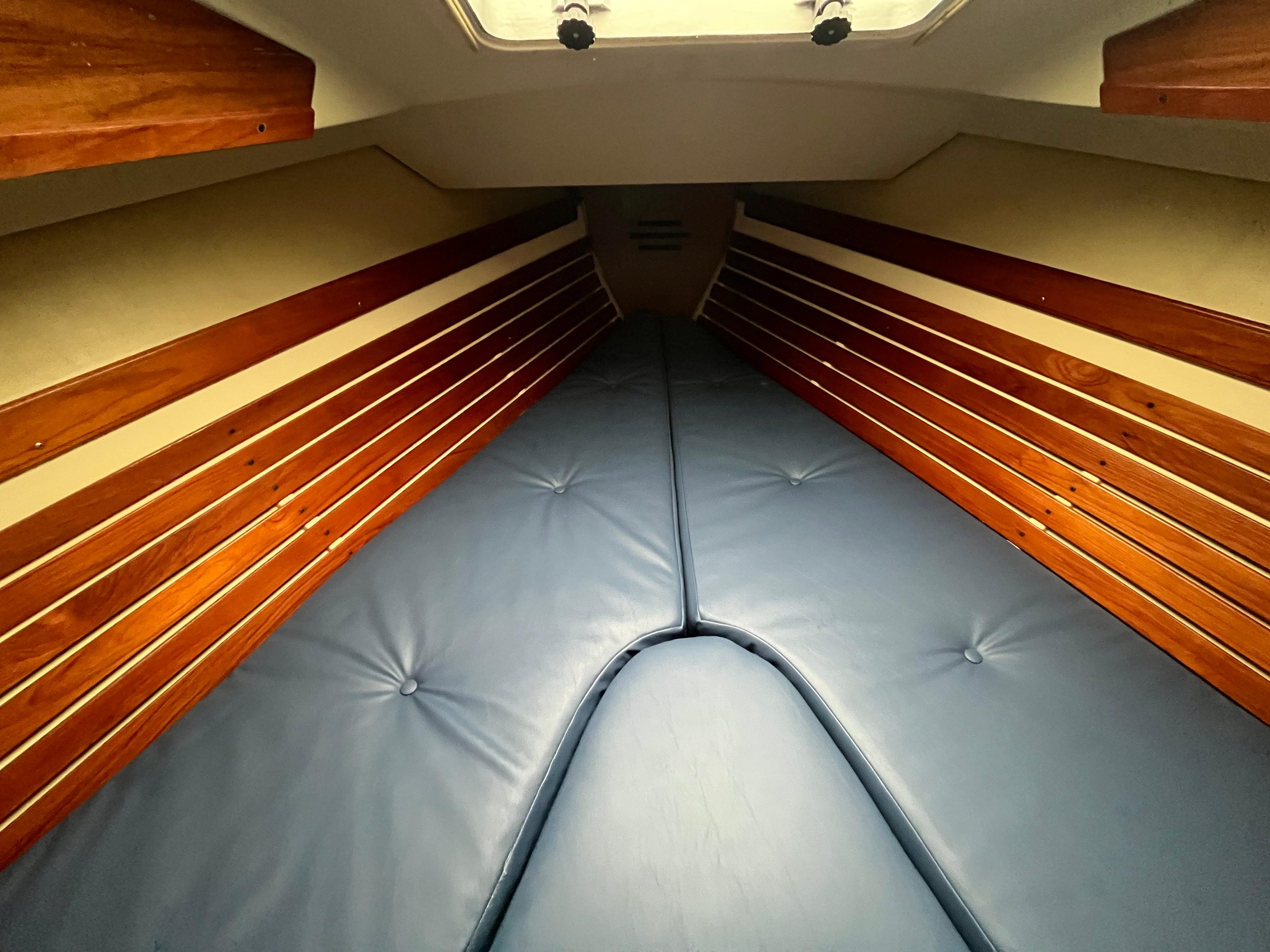 Interior cabin of 1986 Pearson 33-2 sailboat with blue cushions and wooden paneling.