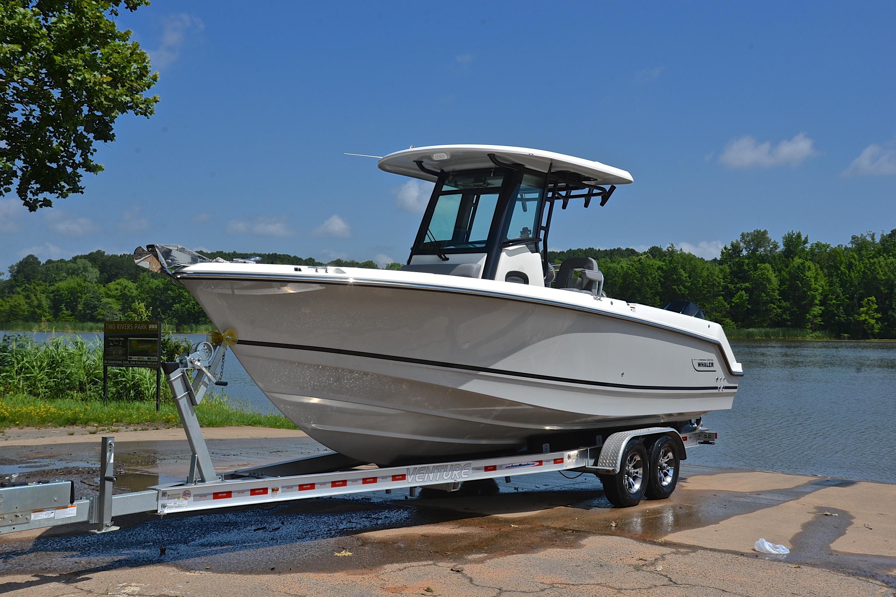 2024 Boston Whaler 250 Outrage boat on trailer by a scenic lake.