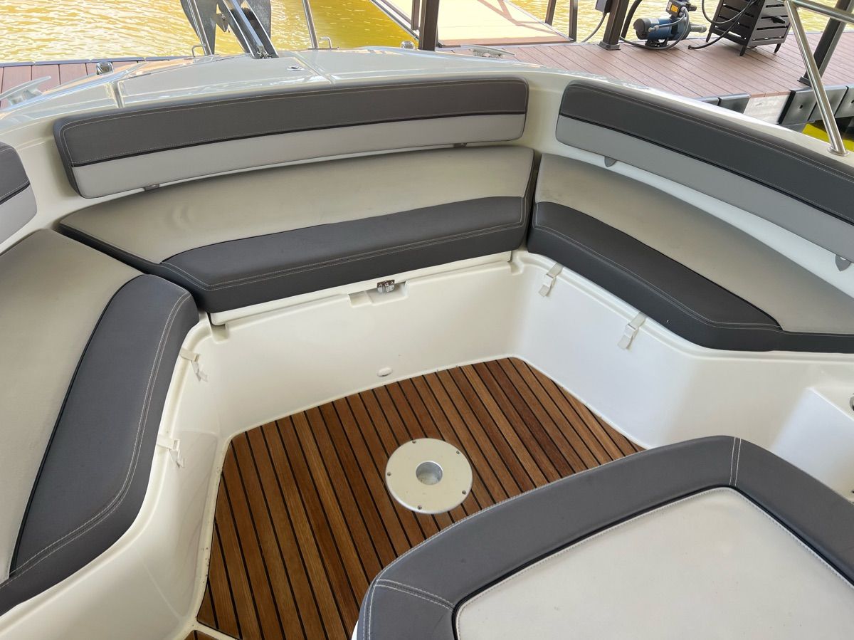 Interior view of a Jeanneau Leader 9 boat with cushioned seating and wooden flooring.