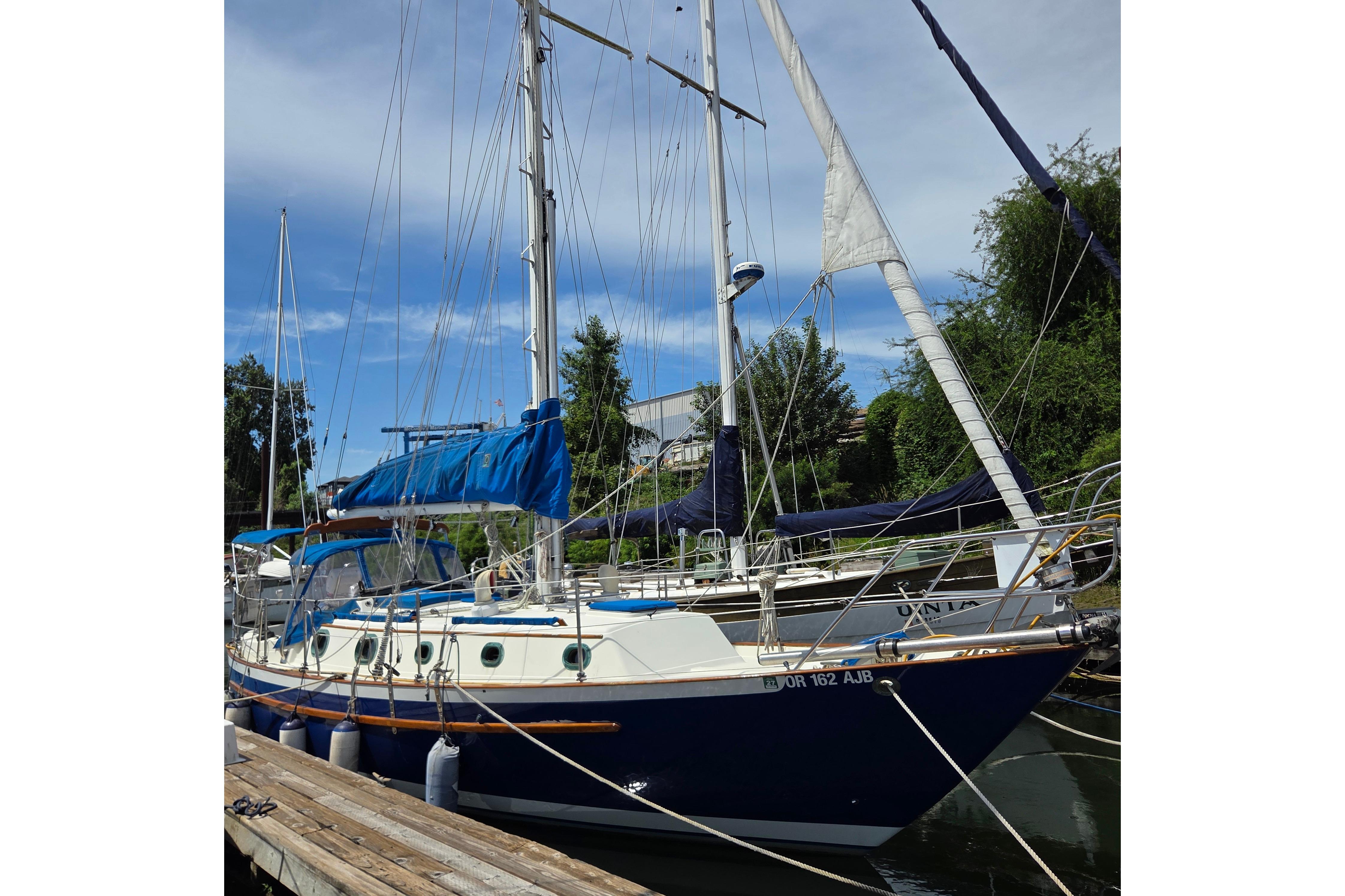 1983 Pacific Seacraft 34 sailboat docked, featuring blue and white design with sails and rigging.